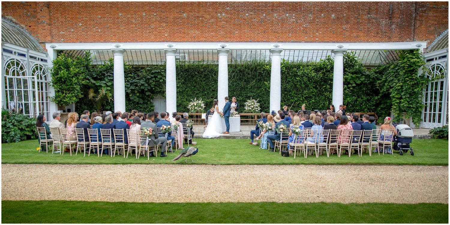 Panoramic view of an outdoor wedding venue with white columns and brick architecture.