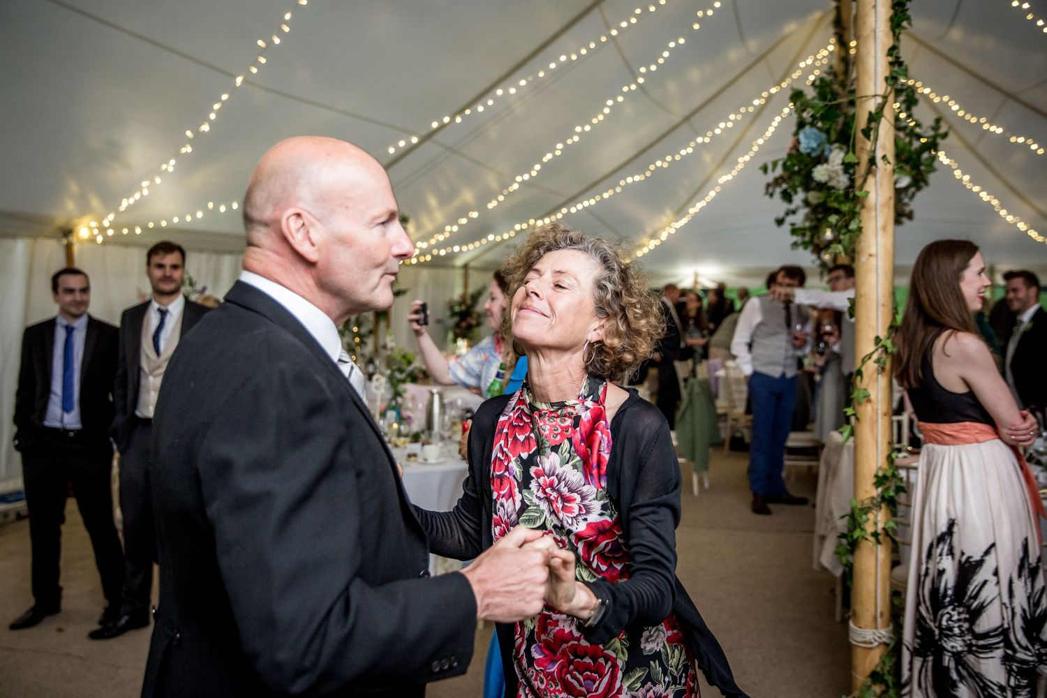 Wedding reception under tent with twinkling lights and rustic decor.