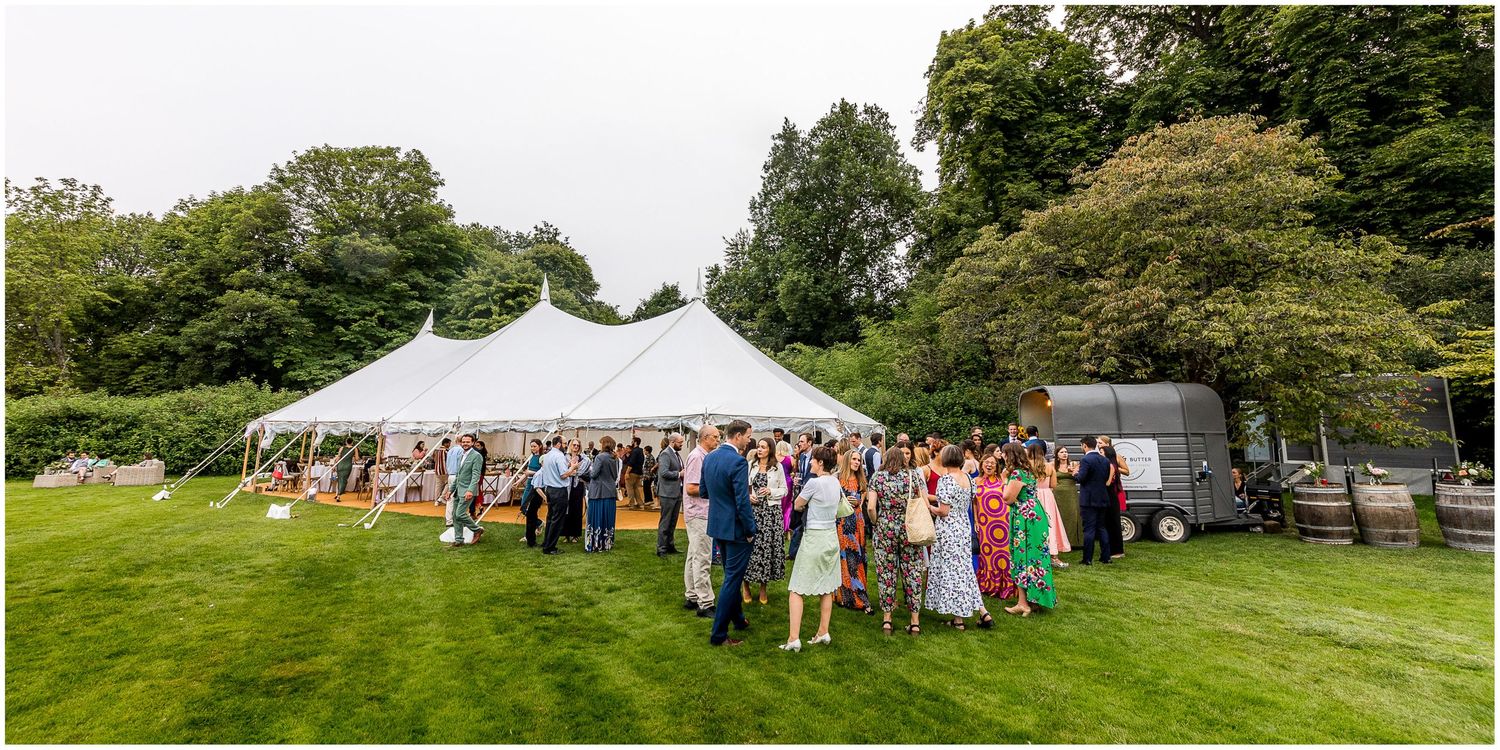 White tent set up in a green field for an outdoor wedding celebration.