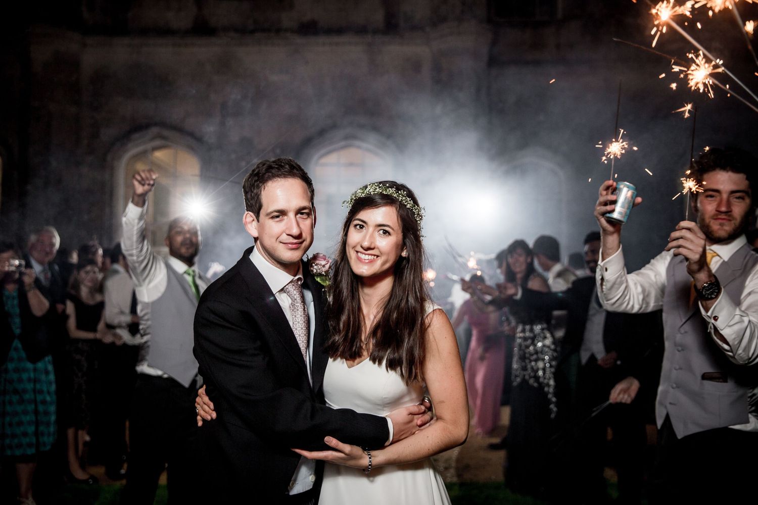 Wedding celebration with sparklers creating magical light effects in a dark venue.