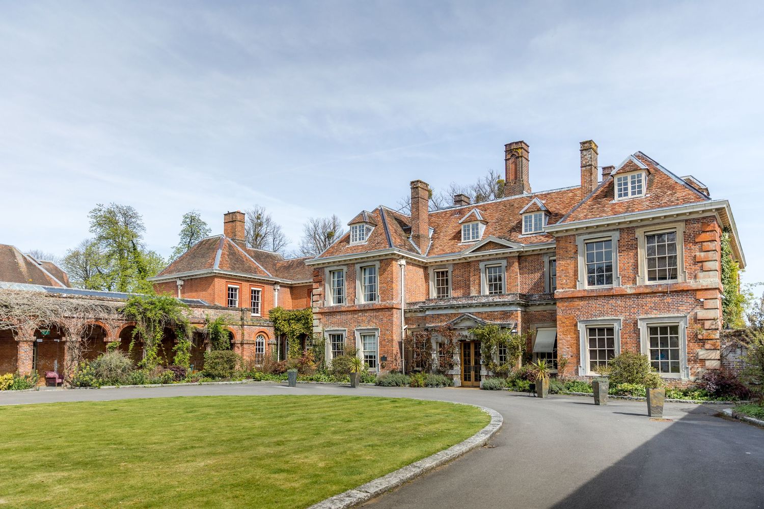 Exterior view of a grand red brick manor house with manicured grounds.