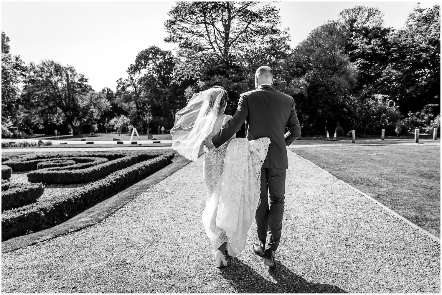 Black and white wedding photography series showing couple walking through scenic garden paths.