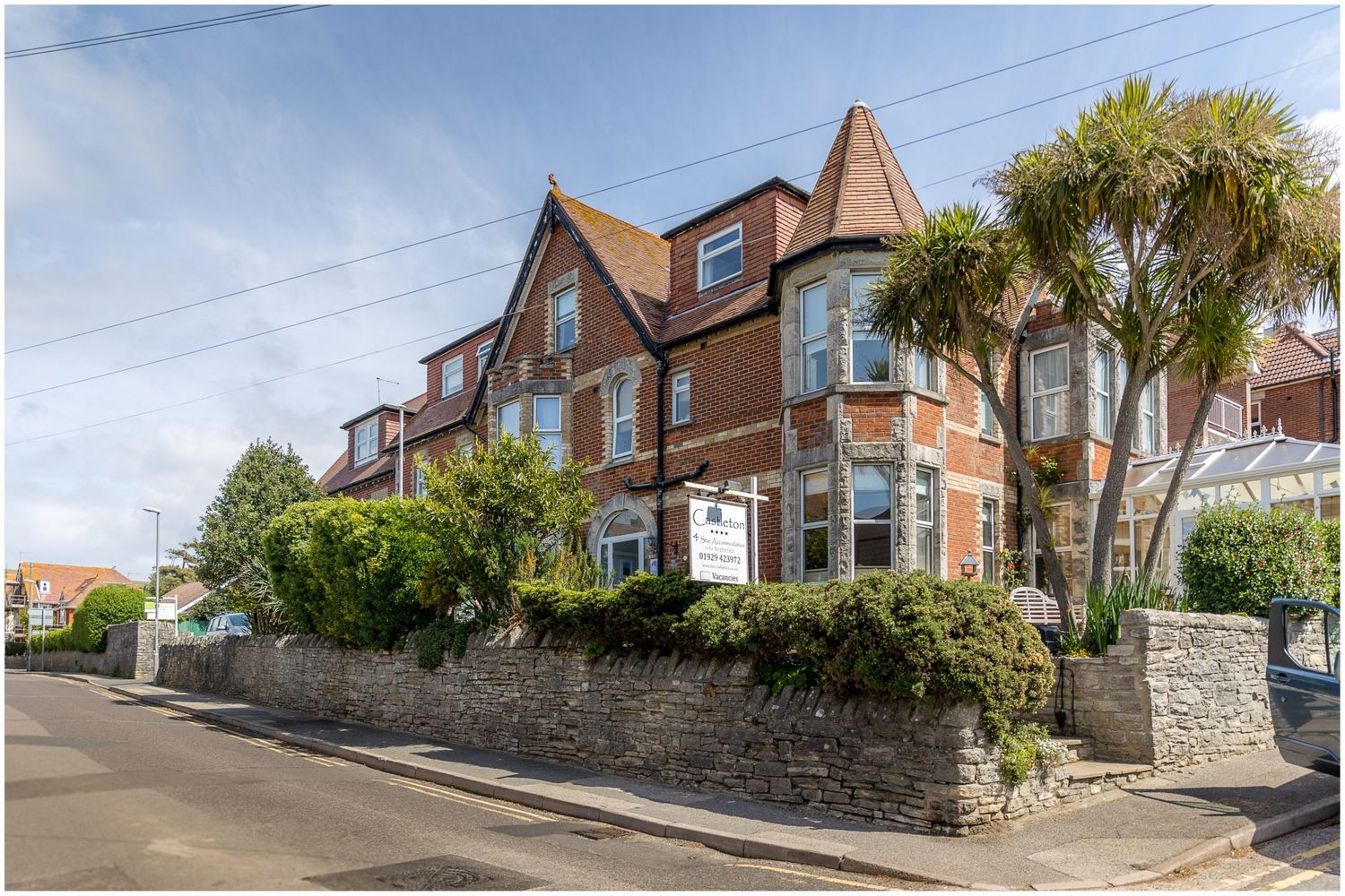 Row of traditional British houses with stone walls and gardens along a residential street.