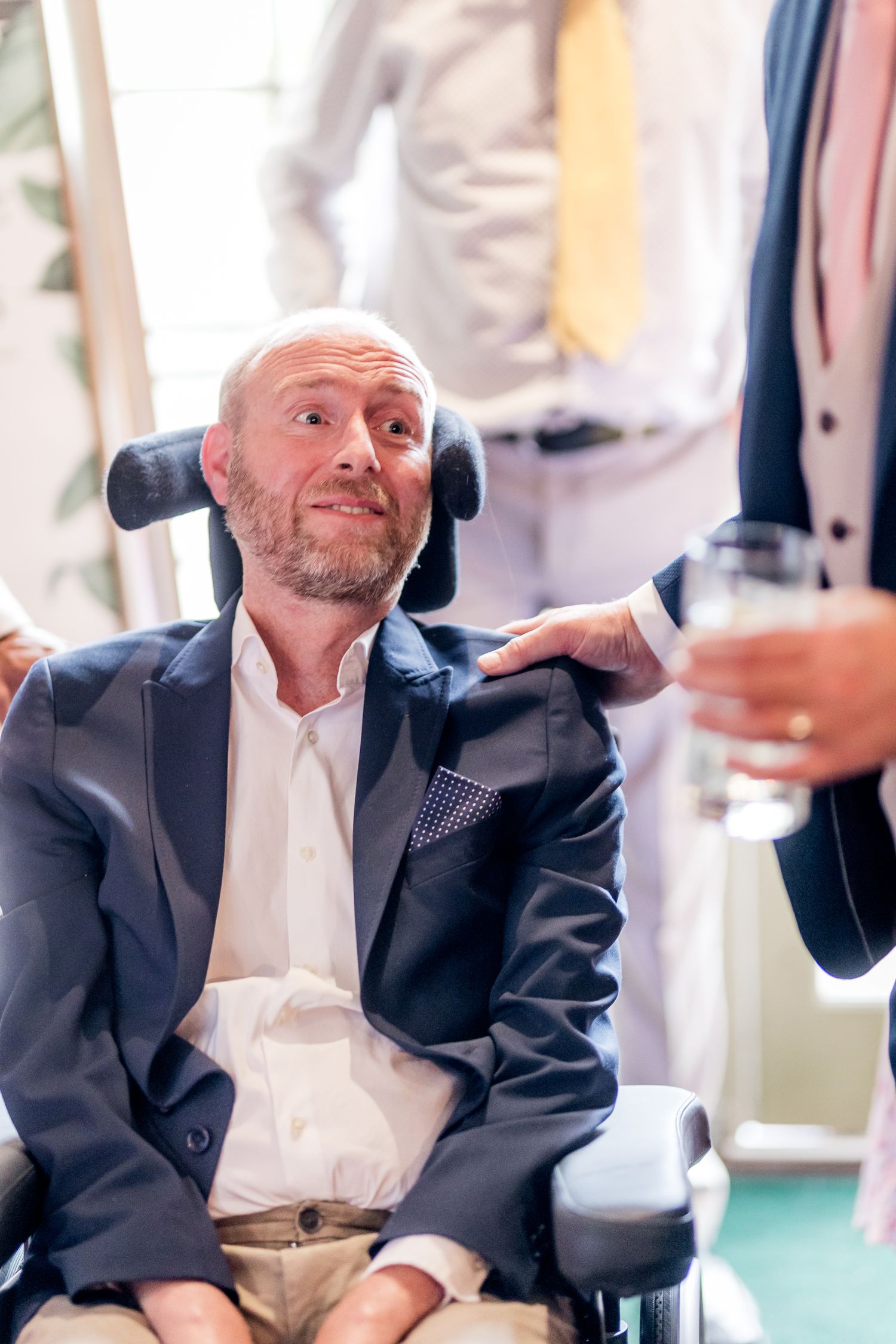 Man in dark suit jacket smiling during a social gathering.