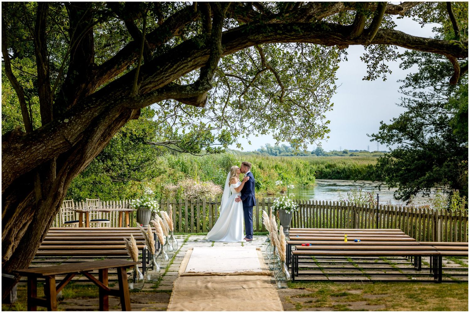 A bride and groom posed in the outdoor ceremony space in the grounds of Sopley Mil, New Forest wedding venue