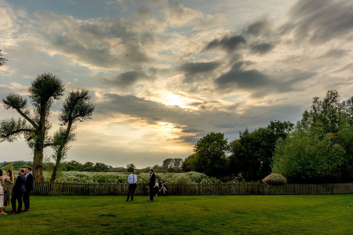 Panoramic sunset views of a rustic outdoor wedding venue with dramatic cloudy skies.