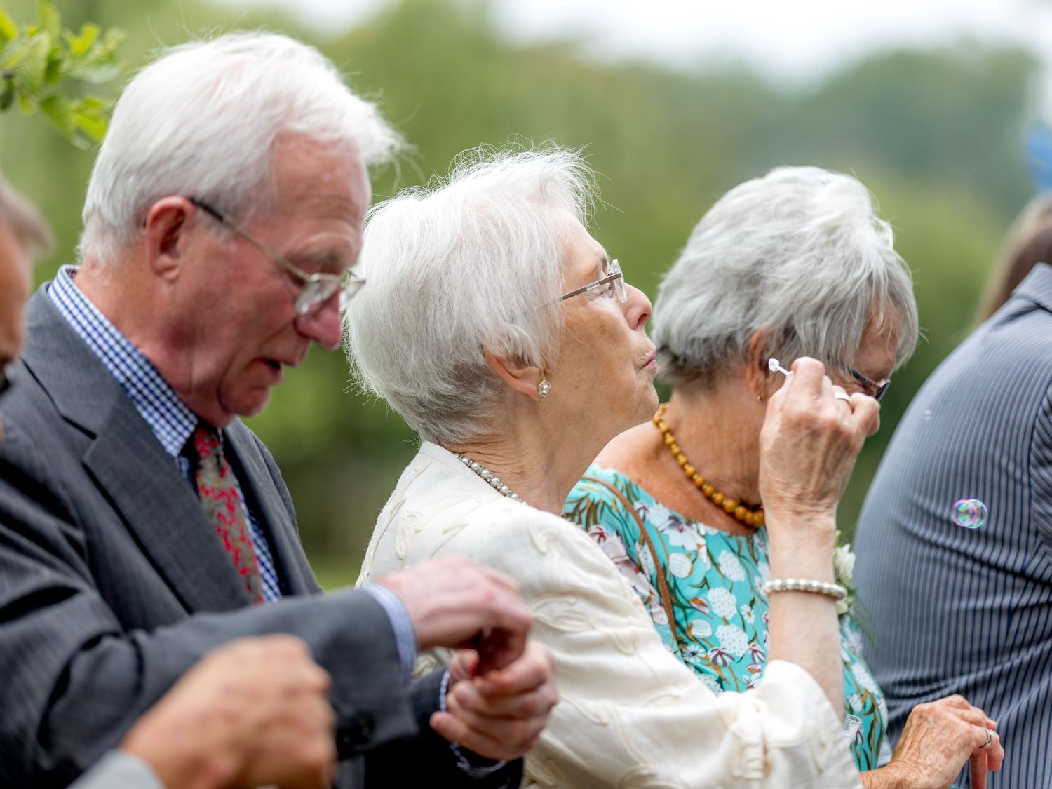 Elderly guests react emotionally during touching wedding moment outdoors.