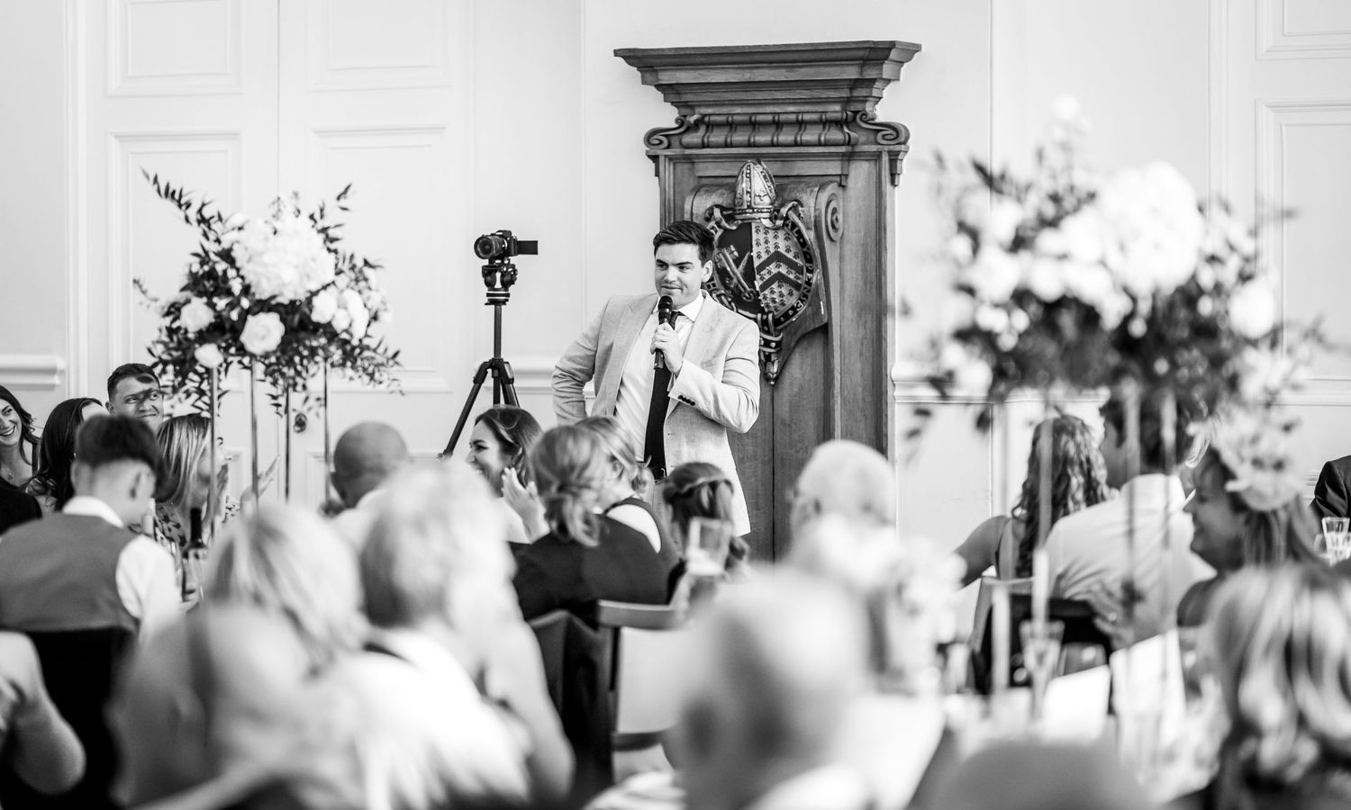 Black and white photo of wedding guests celebrating during an outdoor reception.
