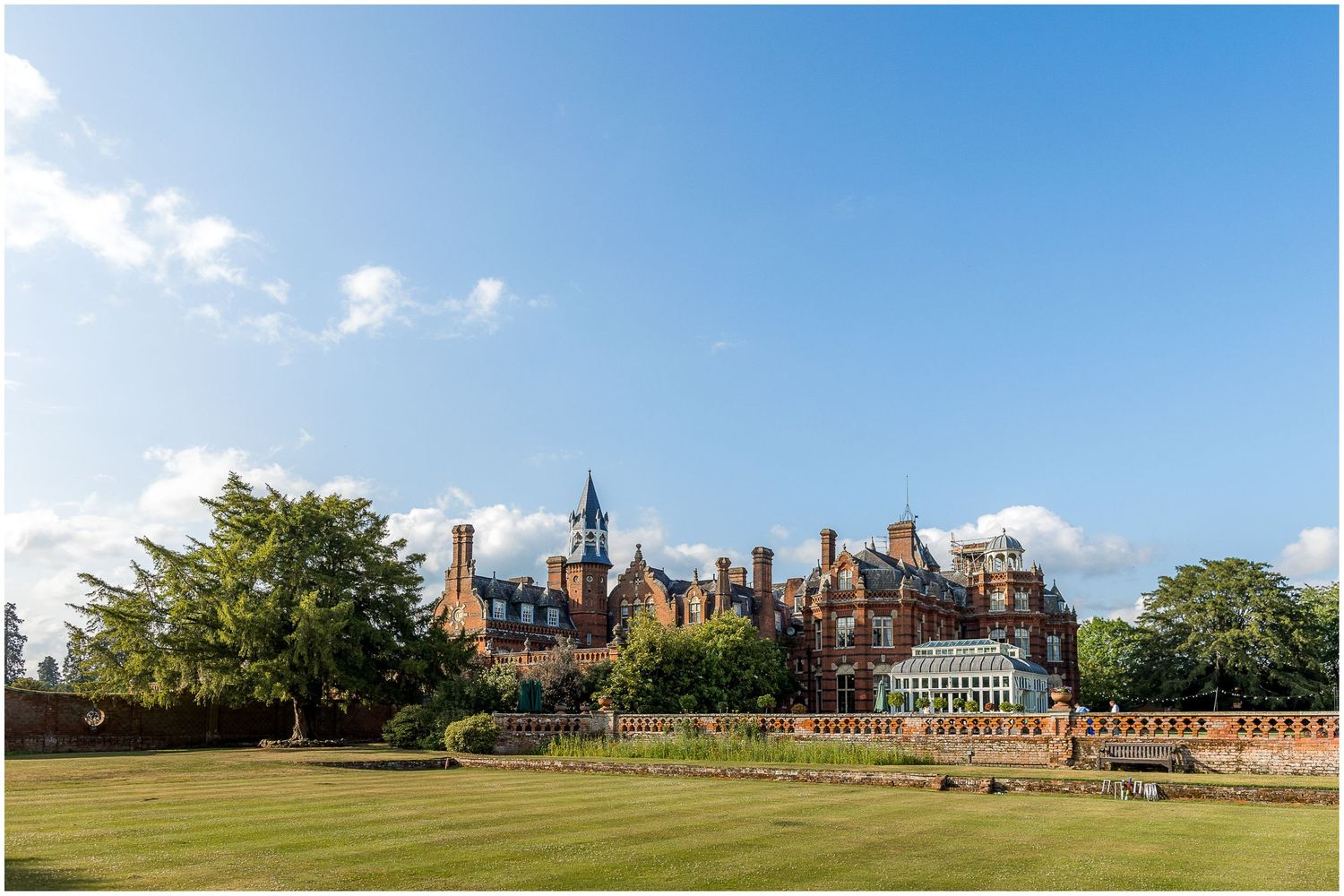A panoramic view of historic Victorian Gothic buildings at Christ Church College in Oxford against a bright blue sky.