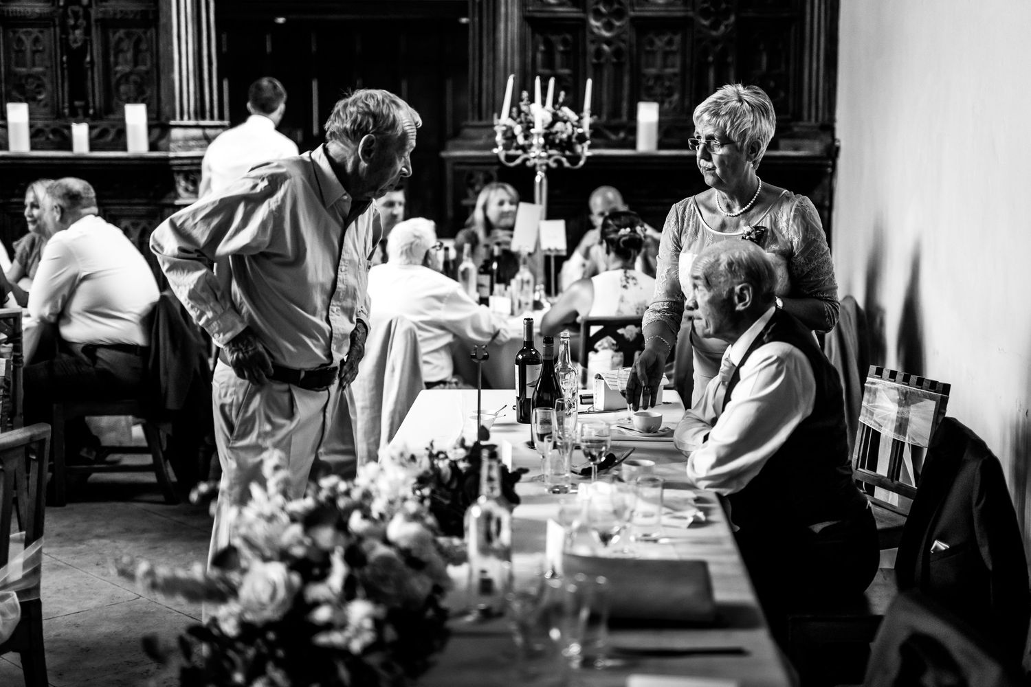 Black and white candid shots of wedding guests enjoying a reception celebration at dining tables.