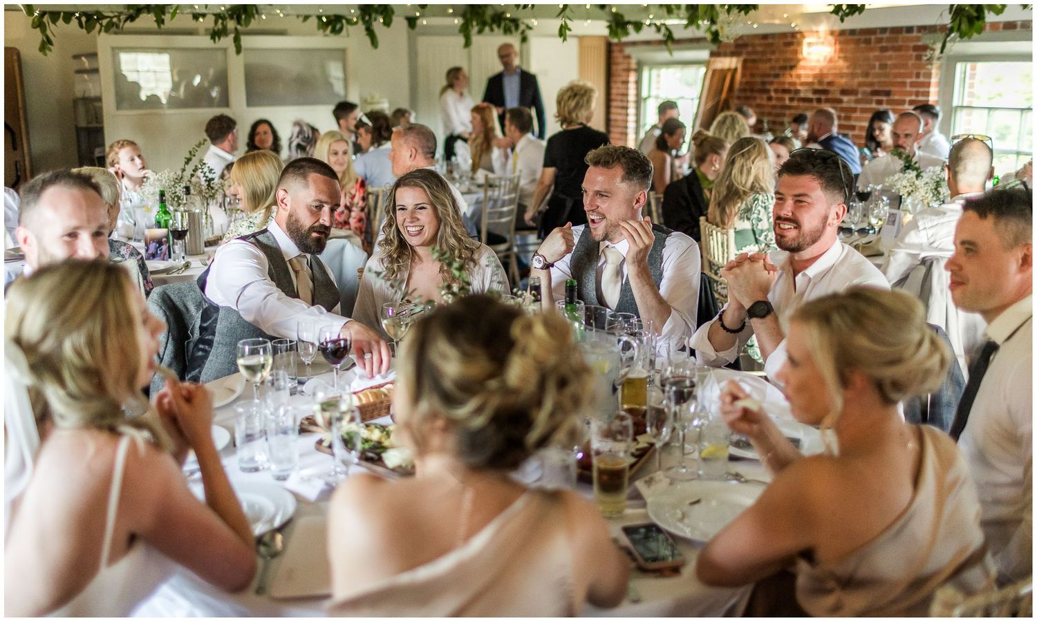 Wedding guests seated at long tables during reception dinner celebration.