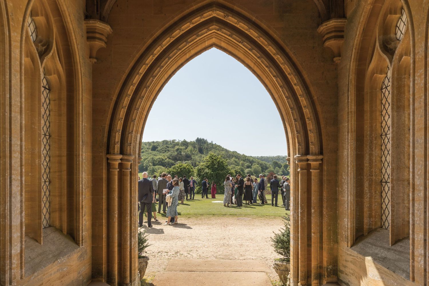 A wedding photography view of the grounds of Milton Abbey School through the church doorway on a sunny day