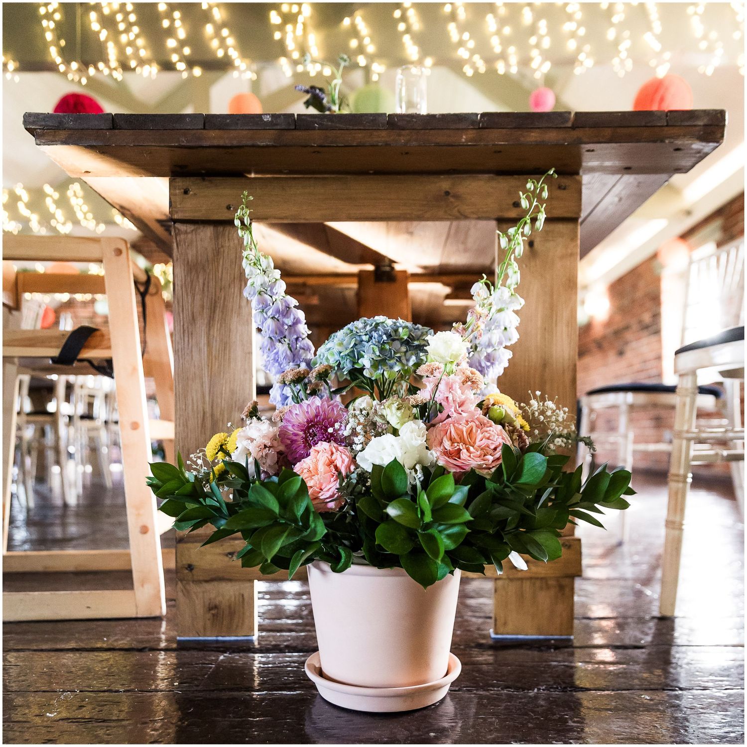 Colorful floral arrangement in a white pot on a wooden table in the dining room at Sopley Mill