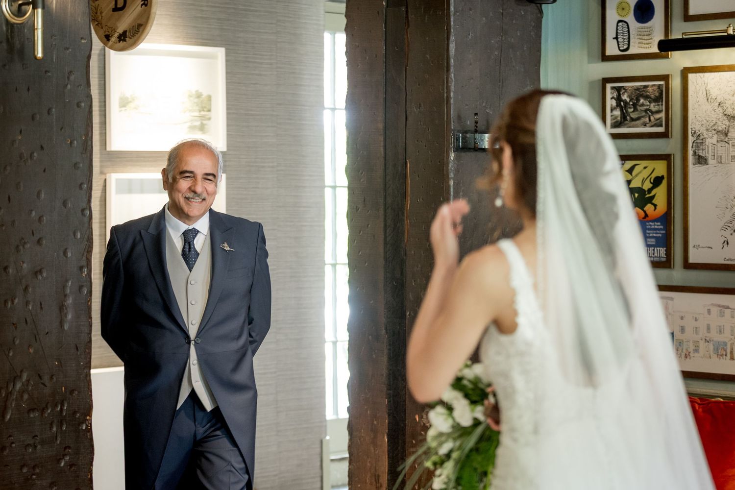 Emotional first look moment between bride and father in a room filled with vintage decor.