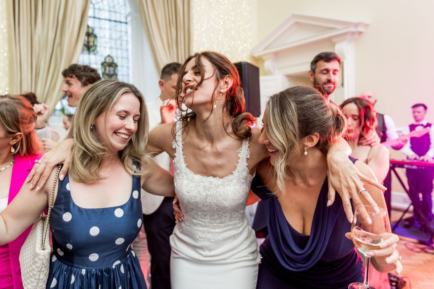 Wedding party dancing and celebrating with joyful expressions in an elegant indoor venue.