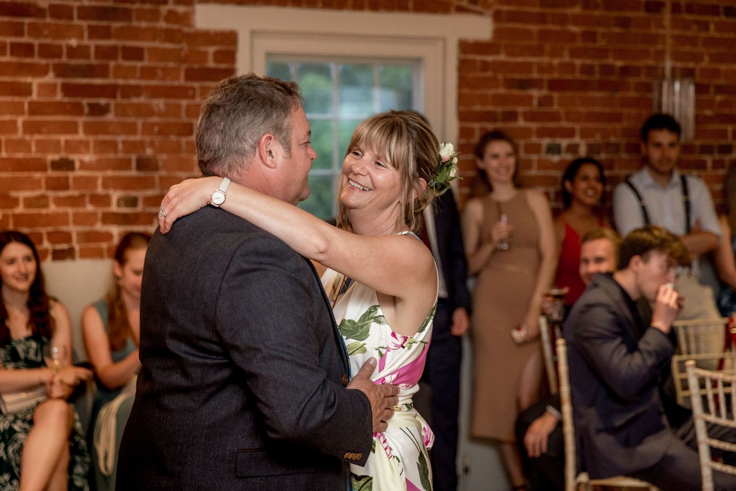 Couples dancing together during a wedding reception in a rustic brick-walled venue.