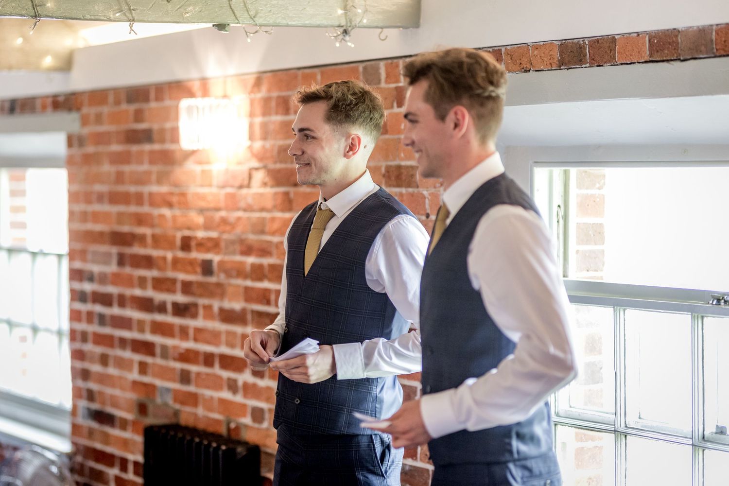 Elegant table settings and floral arrangements at a wedding reception with exposed brick walls.