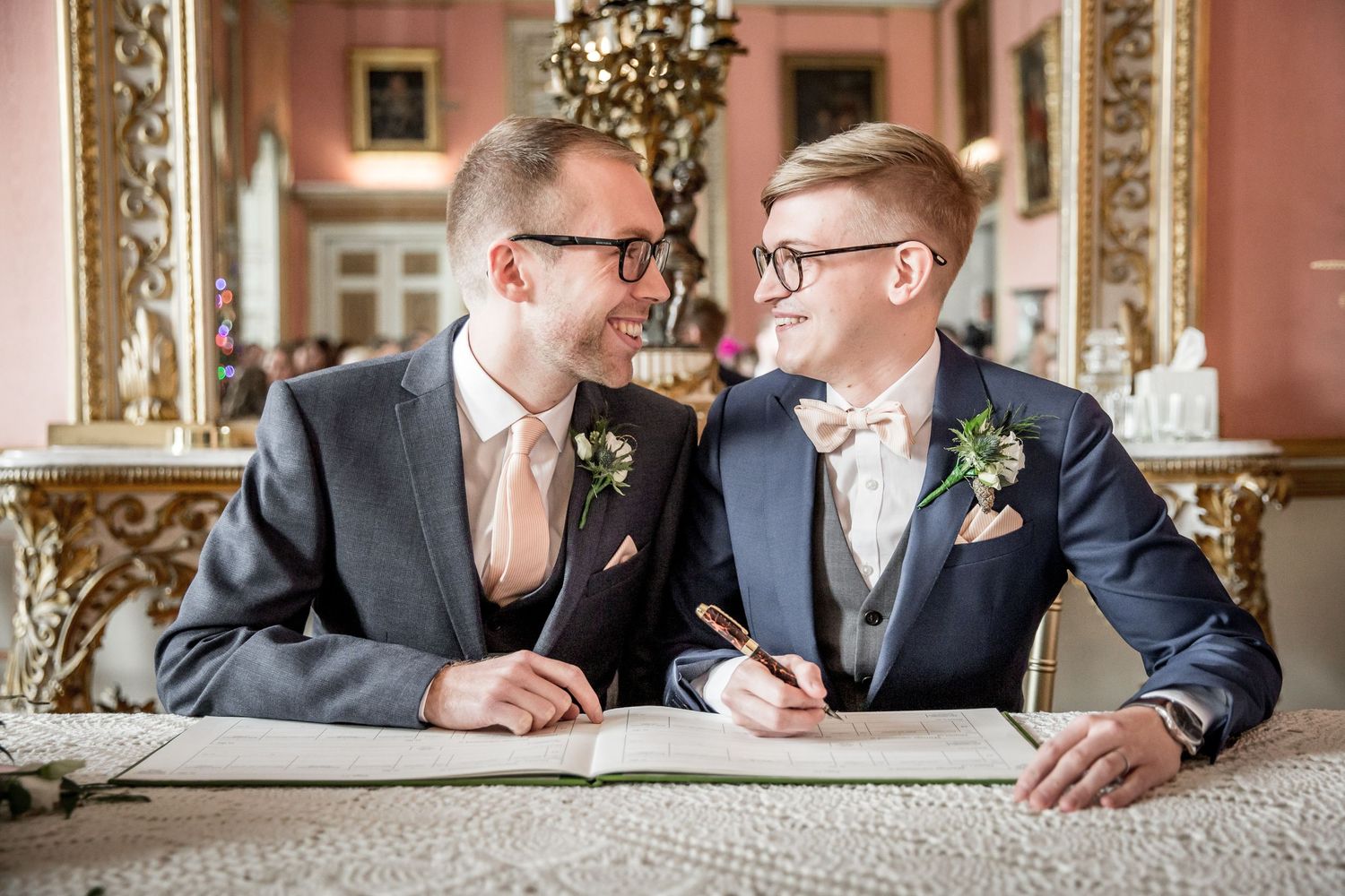 Elegant wedding photos taken in a pink-walled room with ornate gold mirrors.