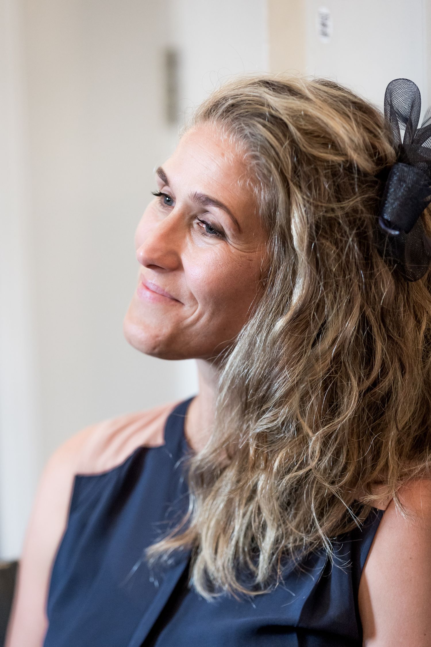 Side profile of wedding guest with curly hair and black hair accessory.