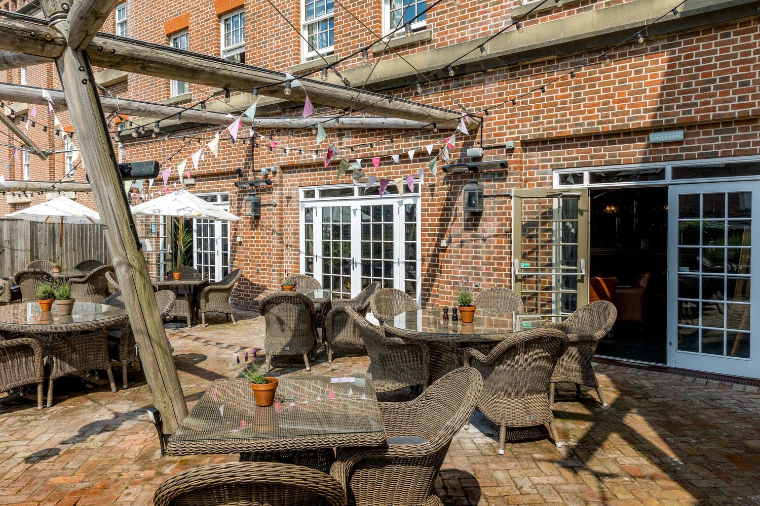 Exterior courtyard of a brick building with wooden beams and outdoor seating area.