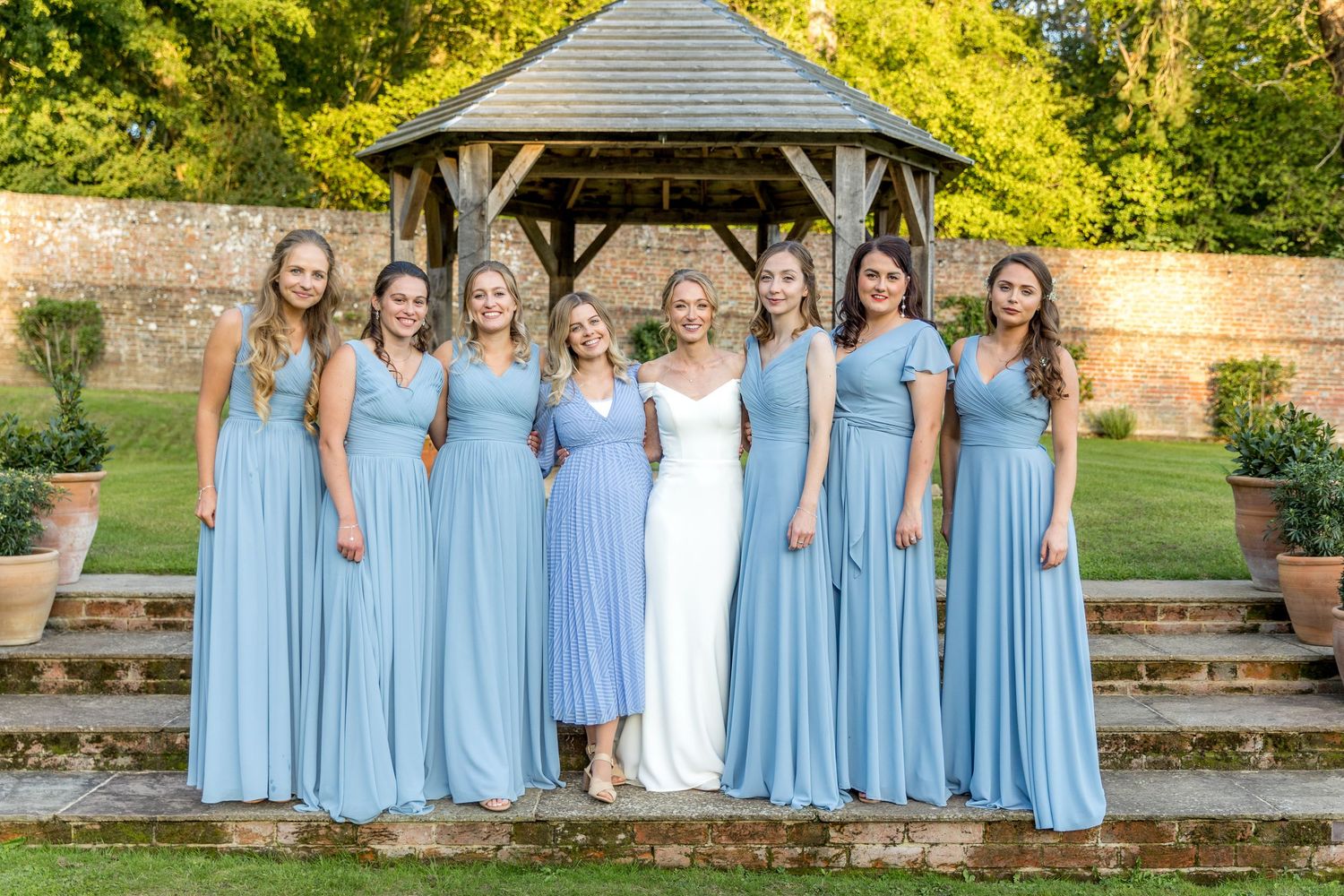 Group photo on stone steps with attendants wearing matching powder blue gowns.