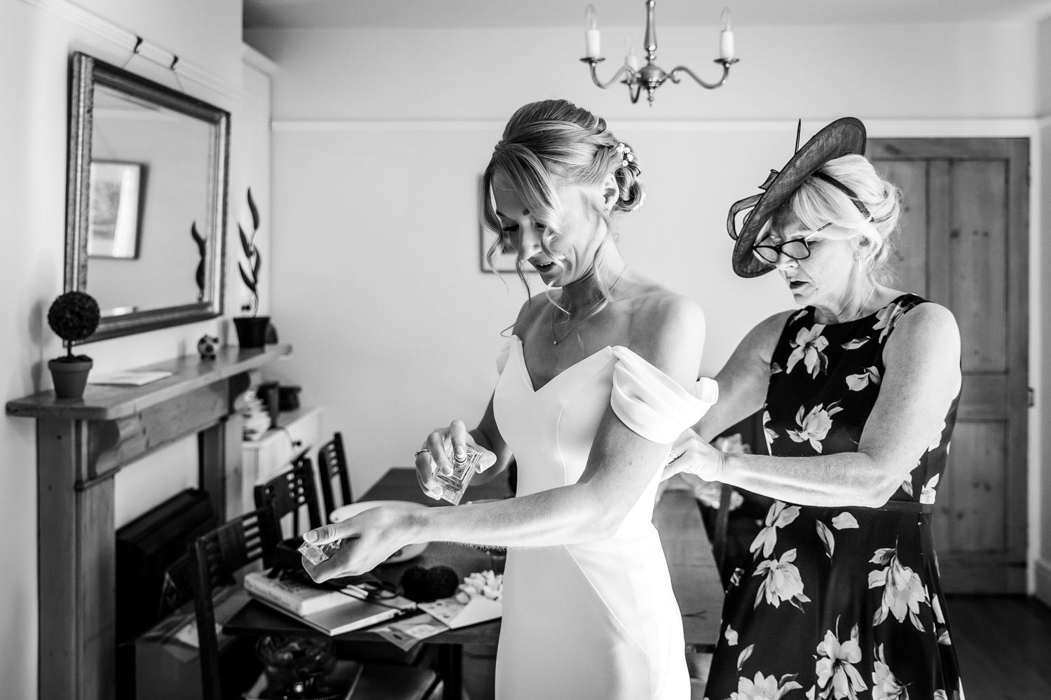 Black and white images of wedding day preparations in an elegant room with chandelier.