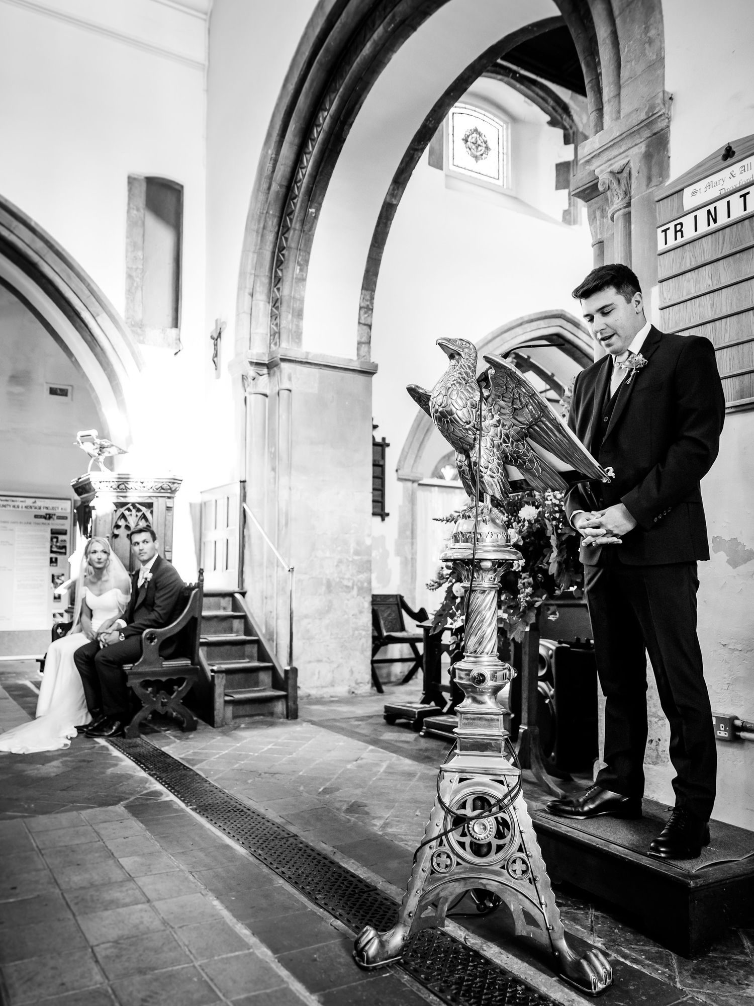Black and white photo of church interior with guests during wedding ceremony.