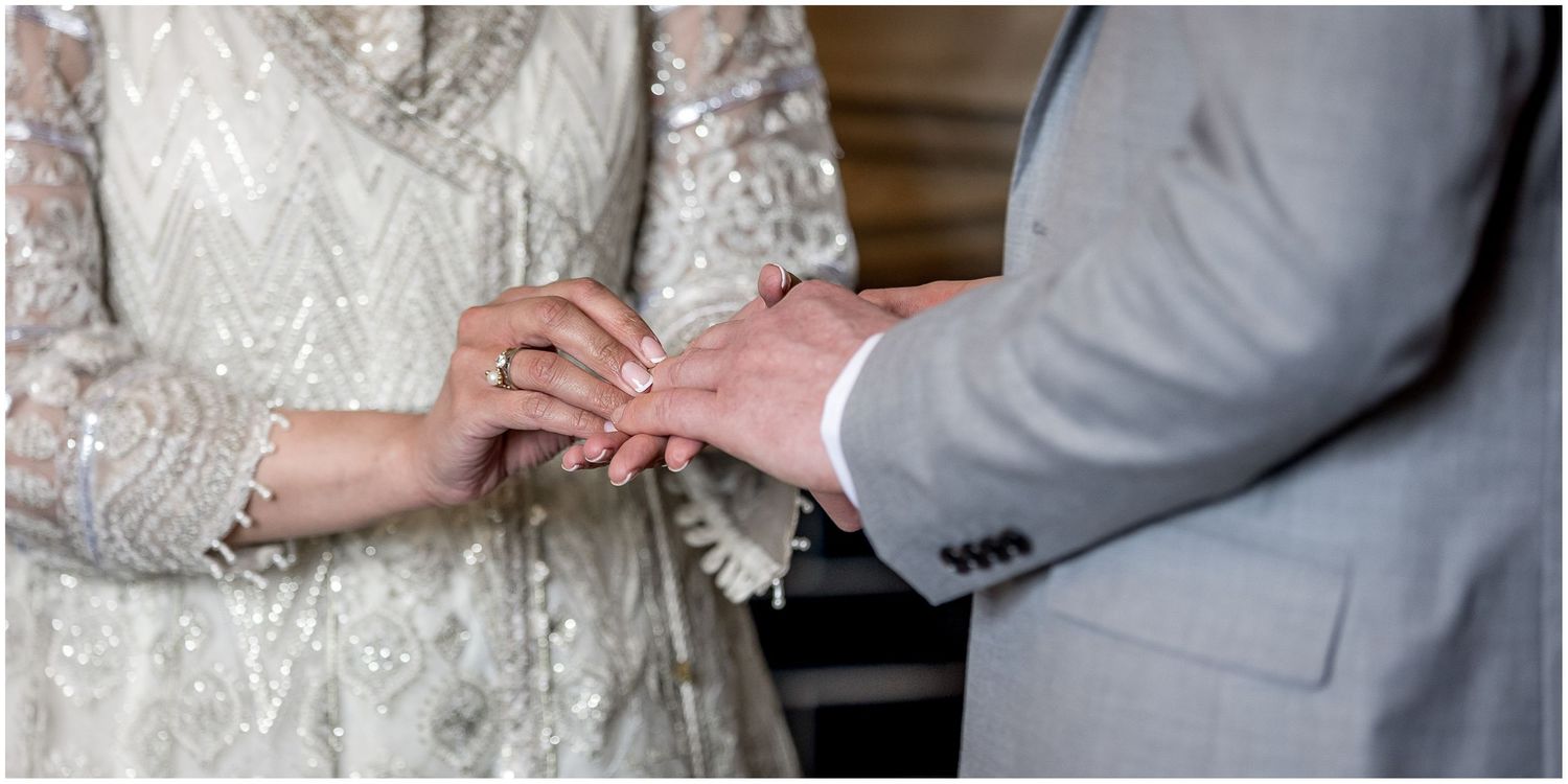 Close-up details of wedding couple's hands and formal attire.