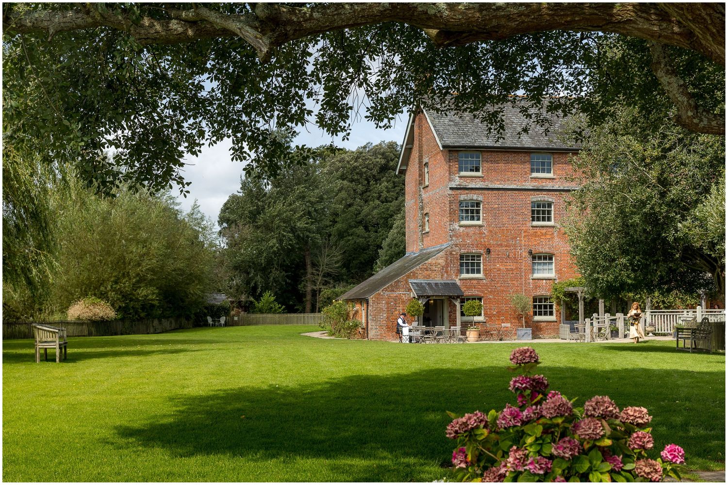 Exterior view of the main building and grounds at Sopley Mill in the height of Summer