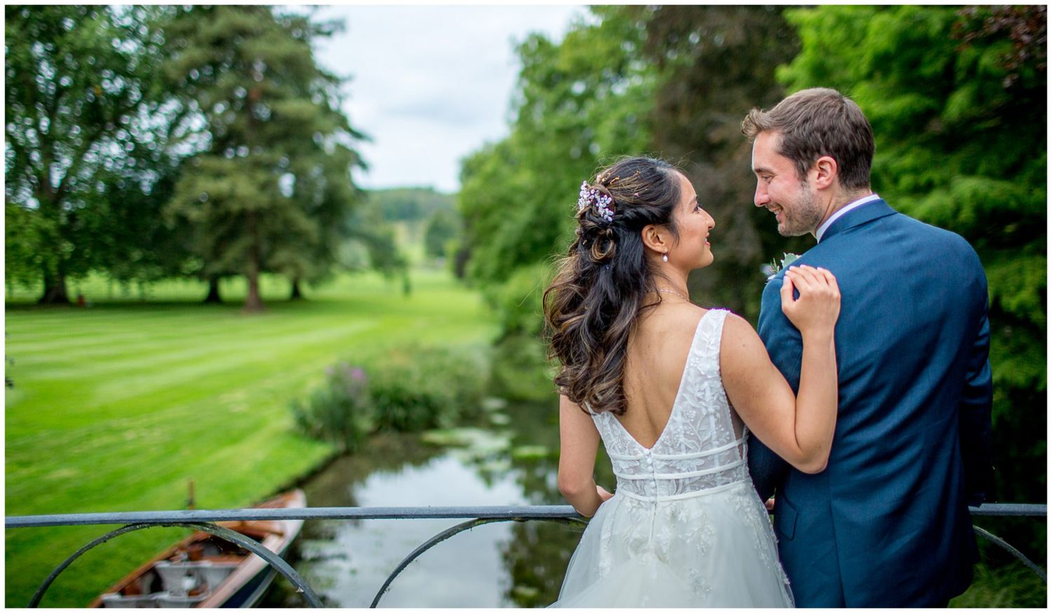 Romantic moment between newlyweds on garden bridge overlooking water.