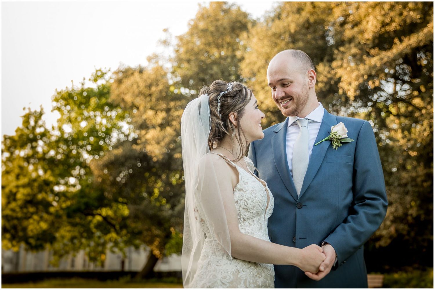 Romantic autumn wedding portraits with golden sunlight filtering through trees.