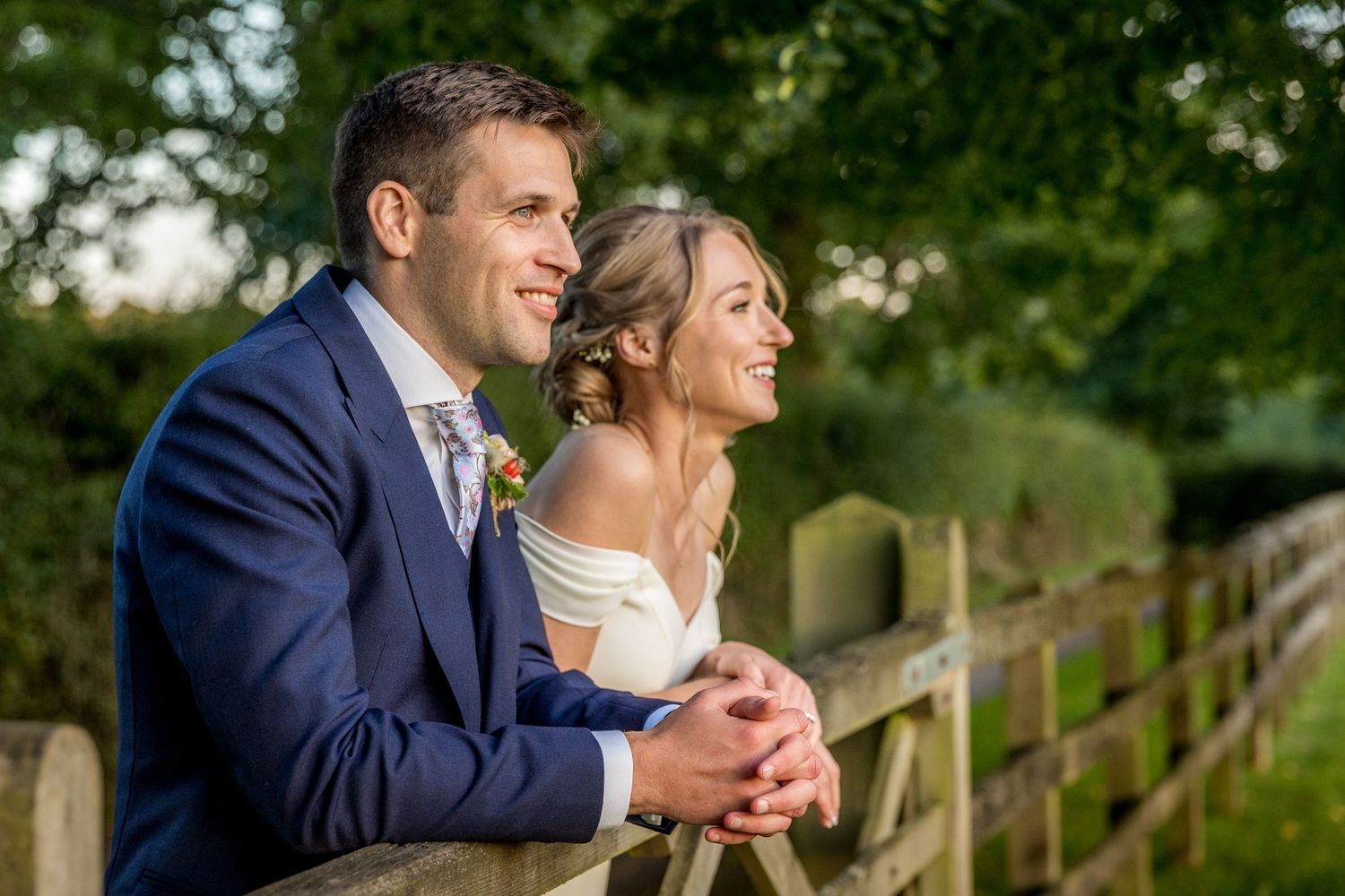 A couple shares a joyful moment together against a backdrop of green foliage.
