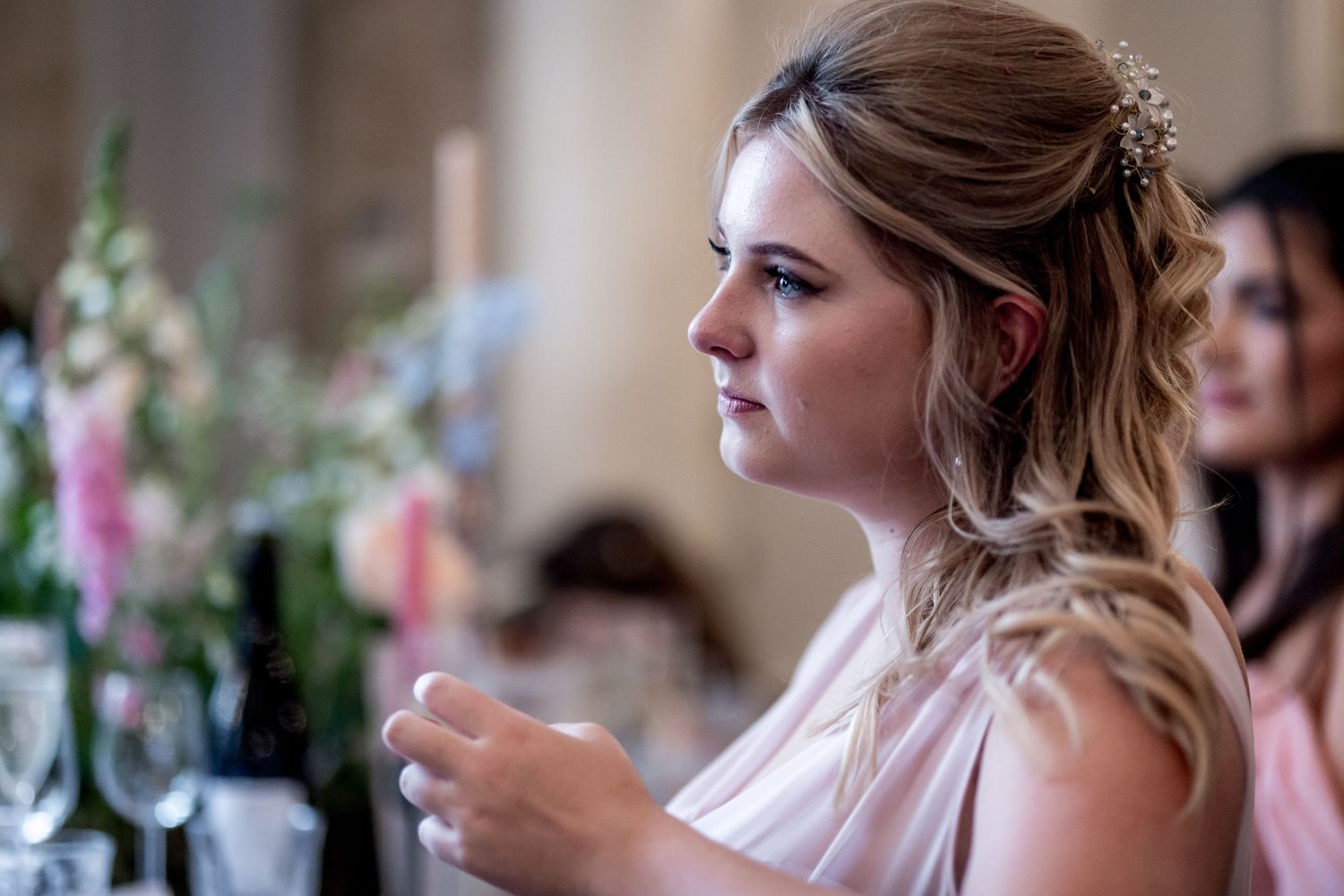 Guests in formal attire listen intently during wedding reception speeches.
