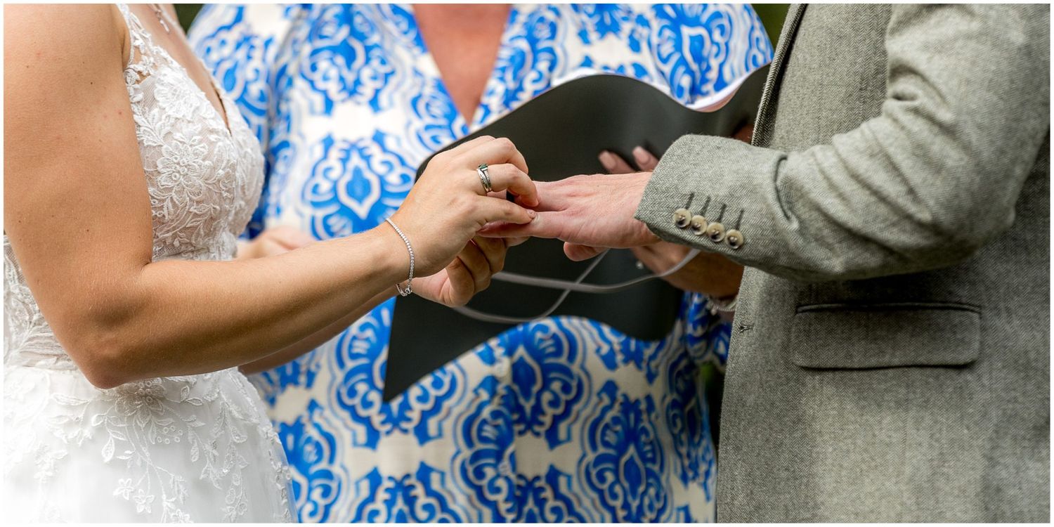 A couple in a blue and white floral dress and gray suit share an intimate moment during their wedding ceremony.
