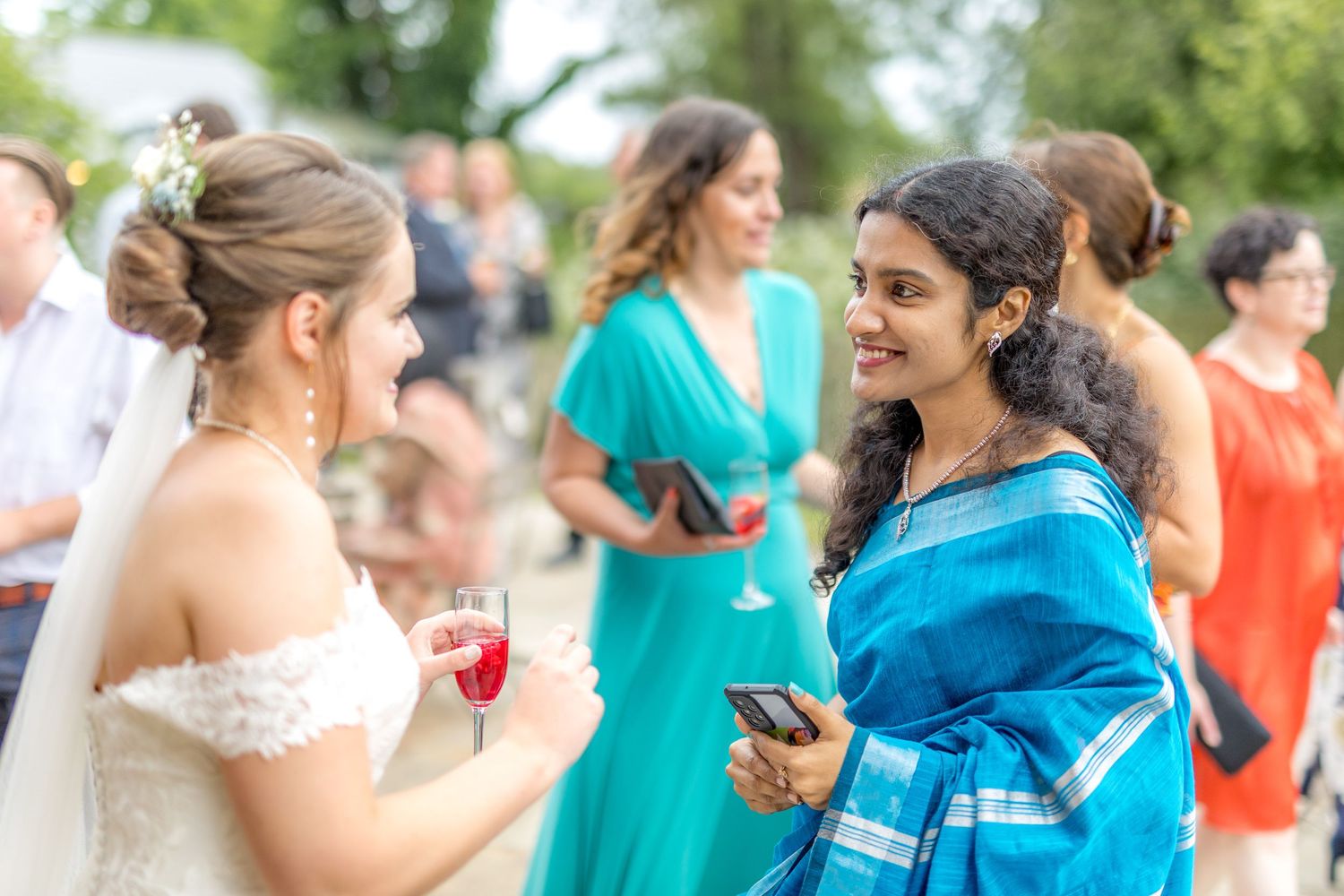 Wedding guests in colorful attire gather during outdoor celebration.