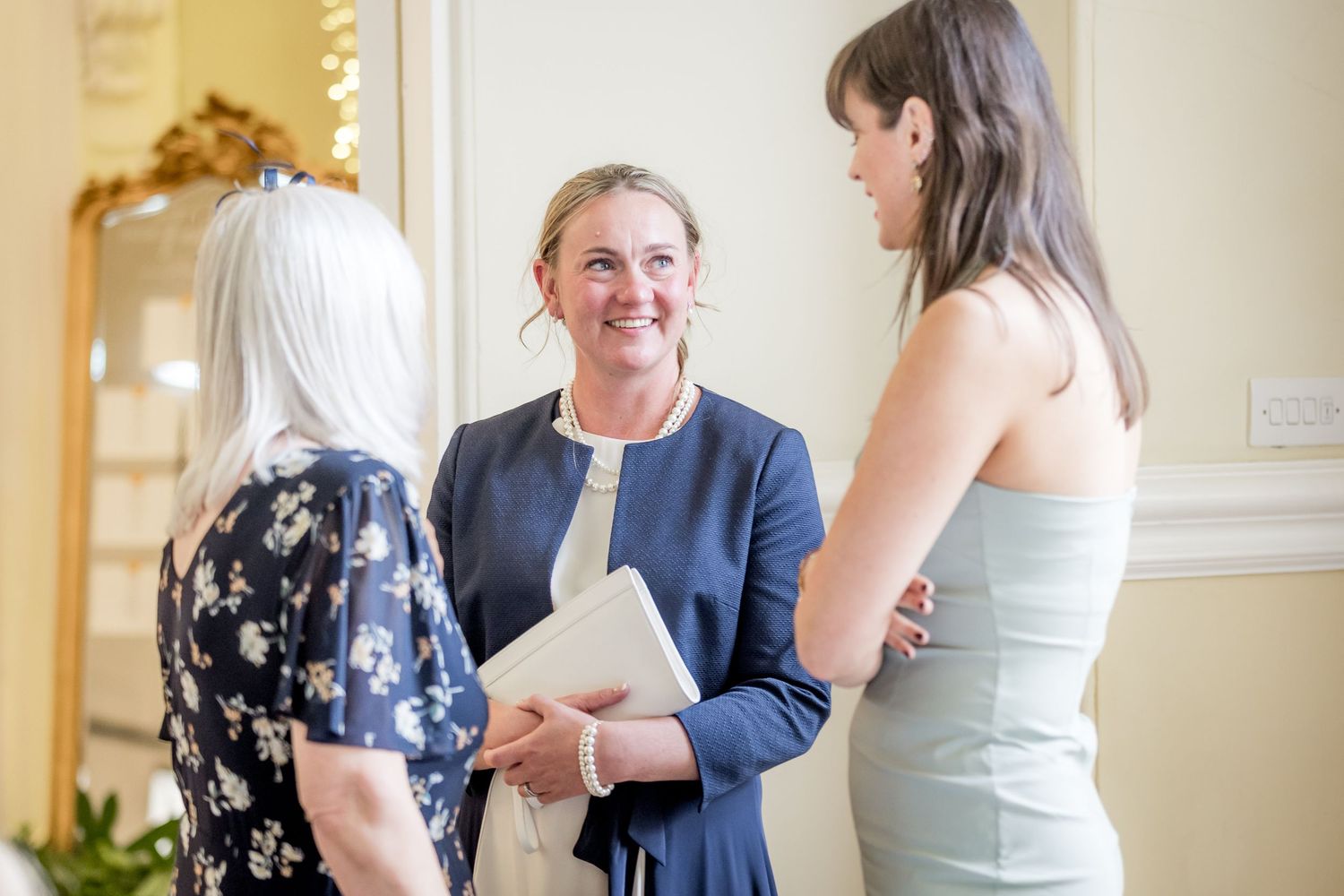 Candid moments captured during a wedding reception in an elegant room with gold accents.