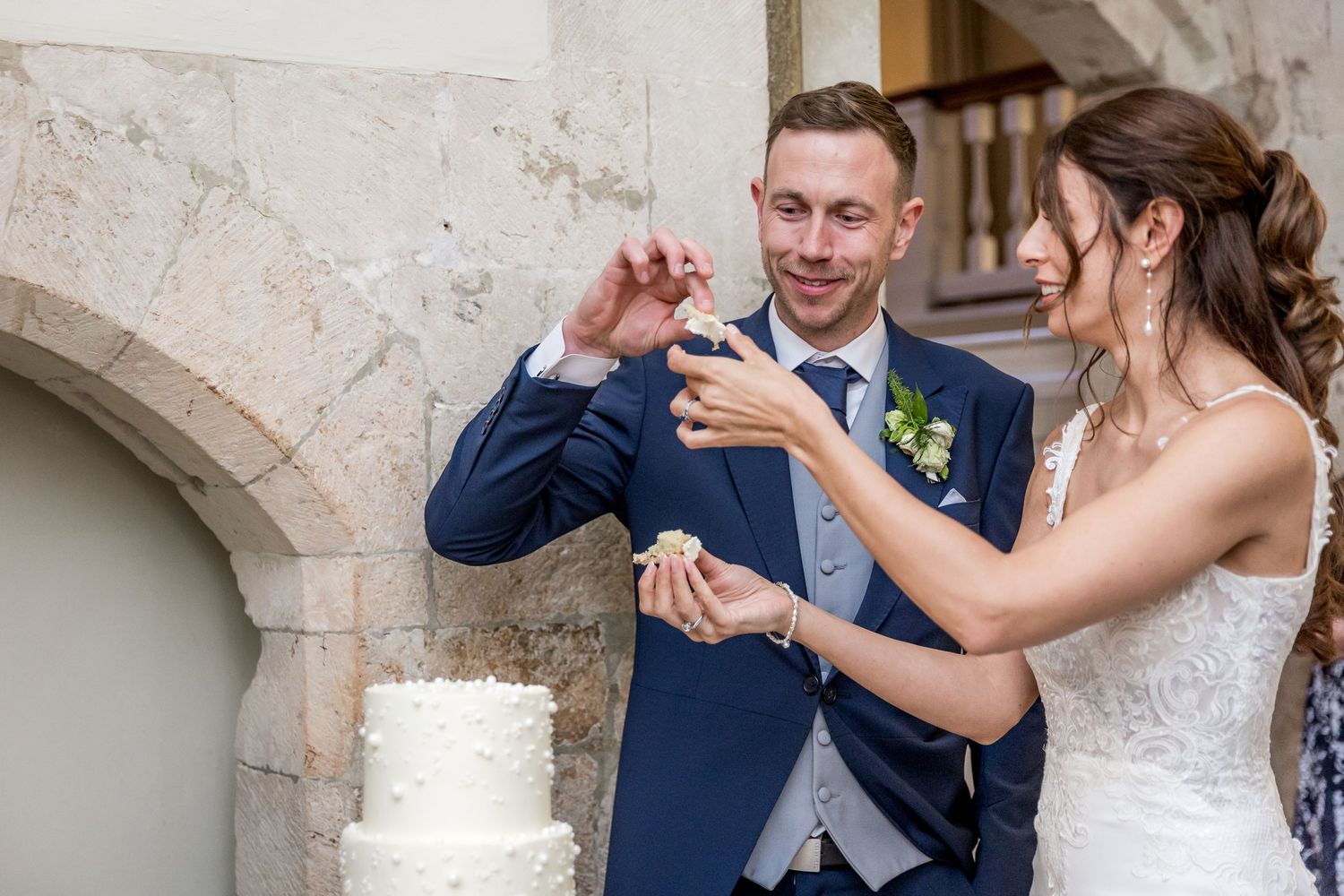 Couple dancing together at their wedding reception near an elegant white tiered cake.