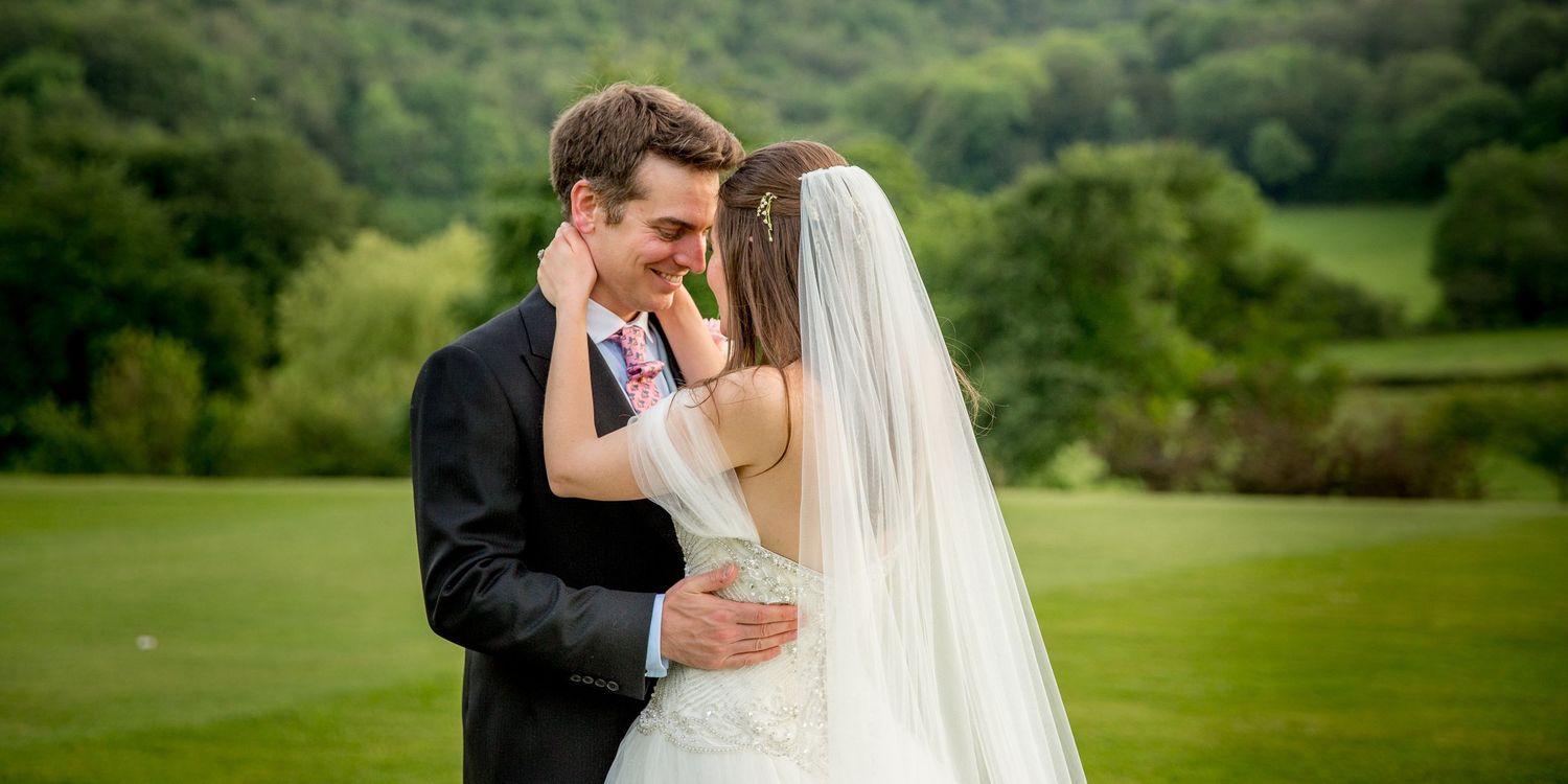 A romantic moment captured between newlyweds on rolling green hills.