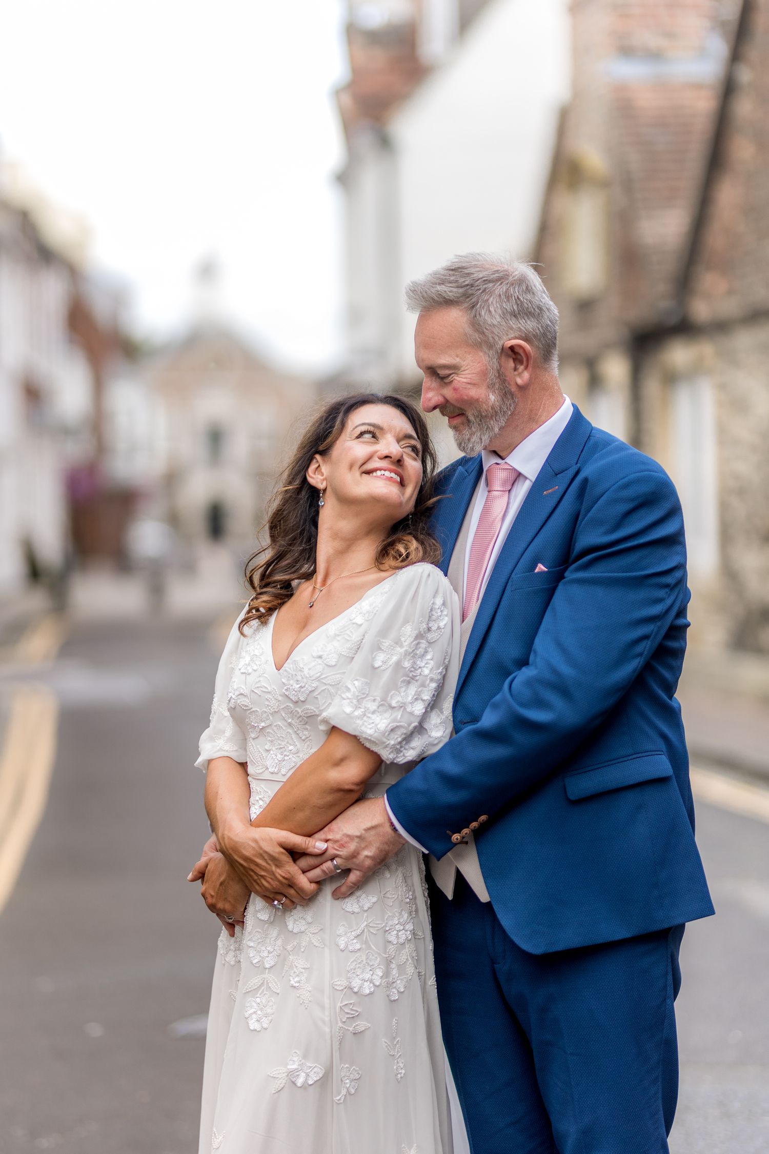 A tender embrace between newlyweds on a peaceful English village street.