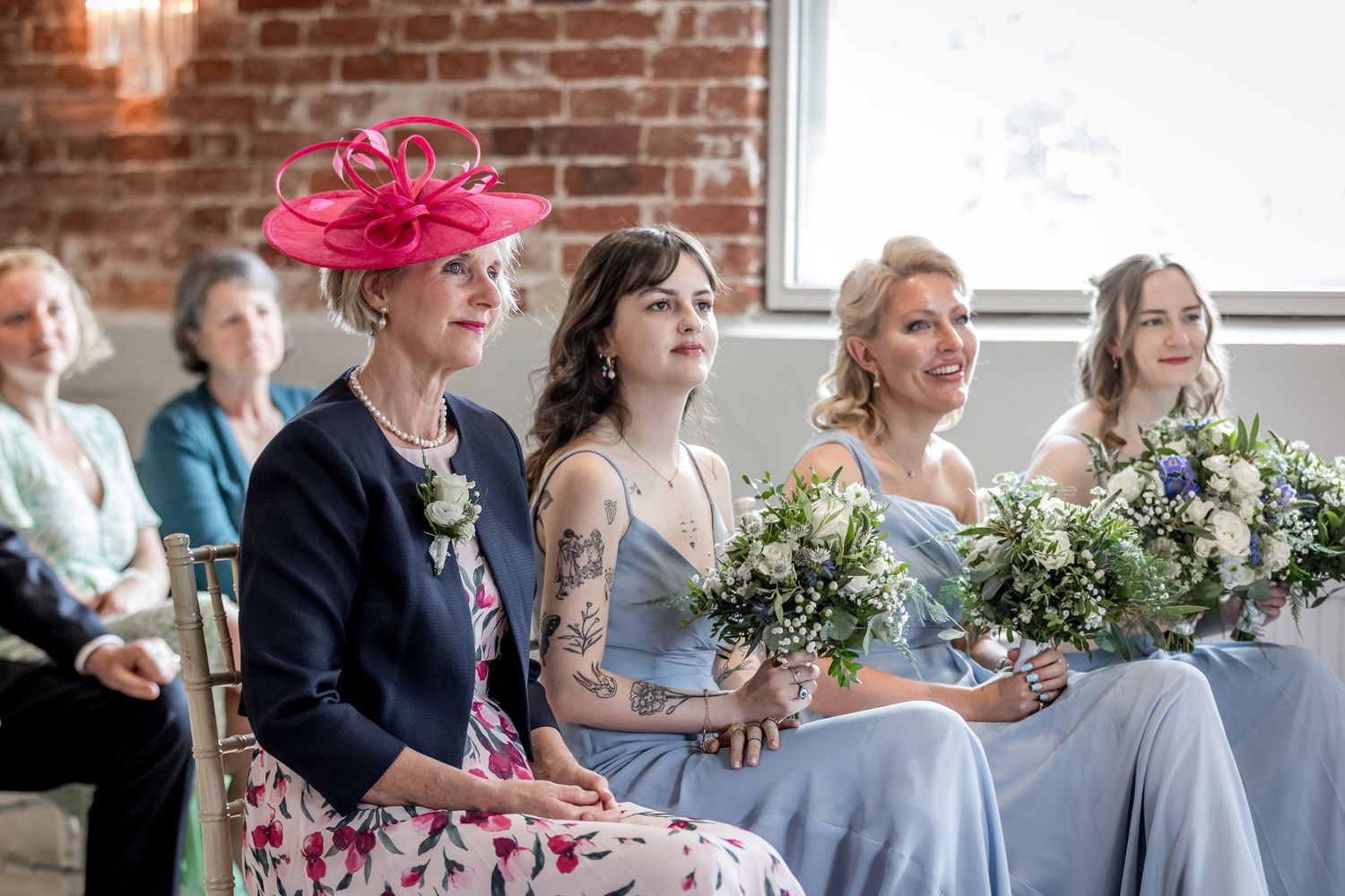 Wedding guests seated in rows watching ceremony in rustic brick venue.