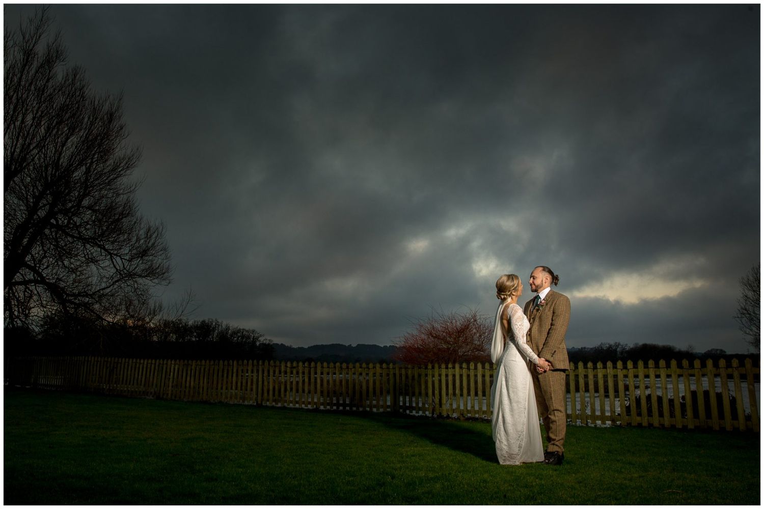 Dramatic stormy sky creates moody backdrop for outdoor wedding photography.