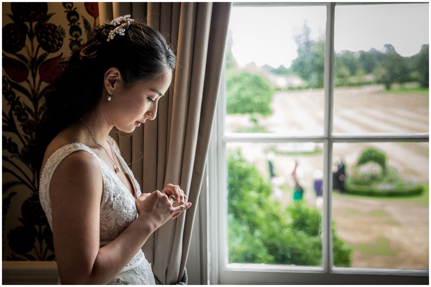 Bride by window in elegant room with natural light streaming through.