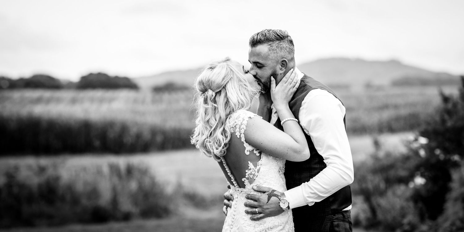 Romantic black and white portrait of couple against scenic mountain backdrop.