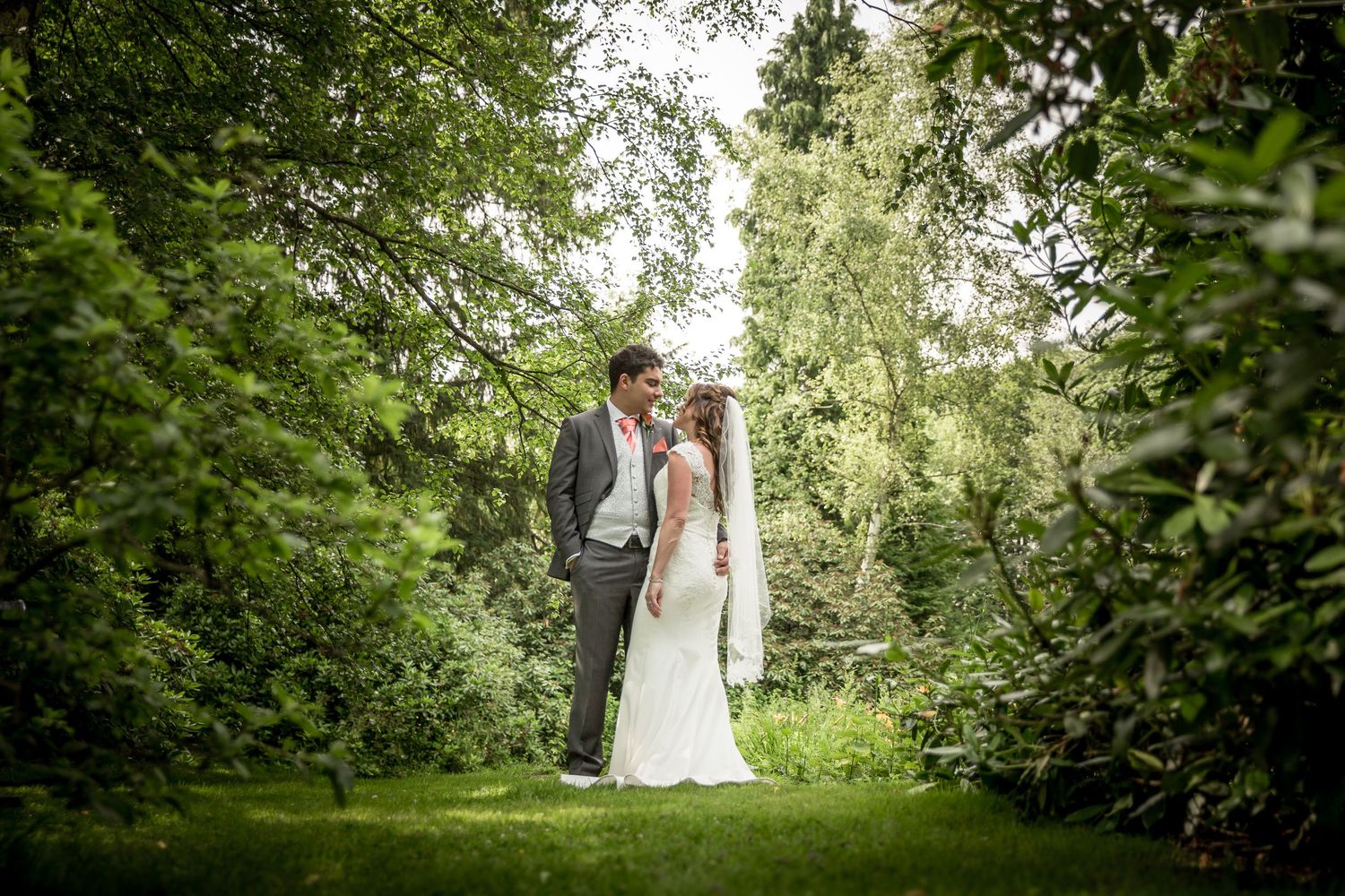 Wedding photography in a lush green garden setting with natural summer lighting.