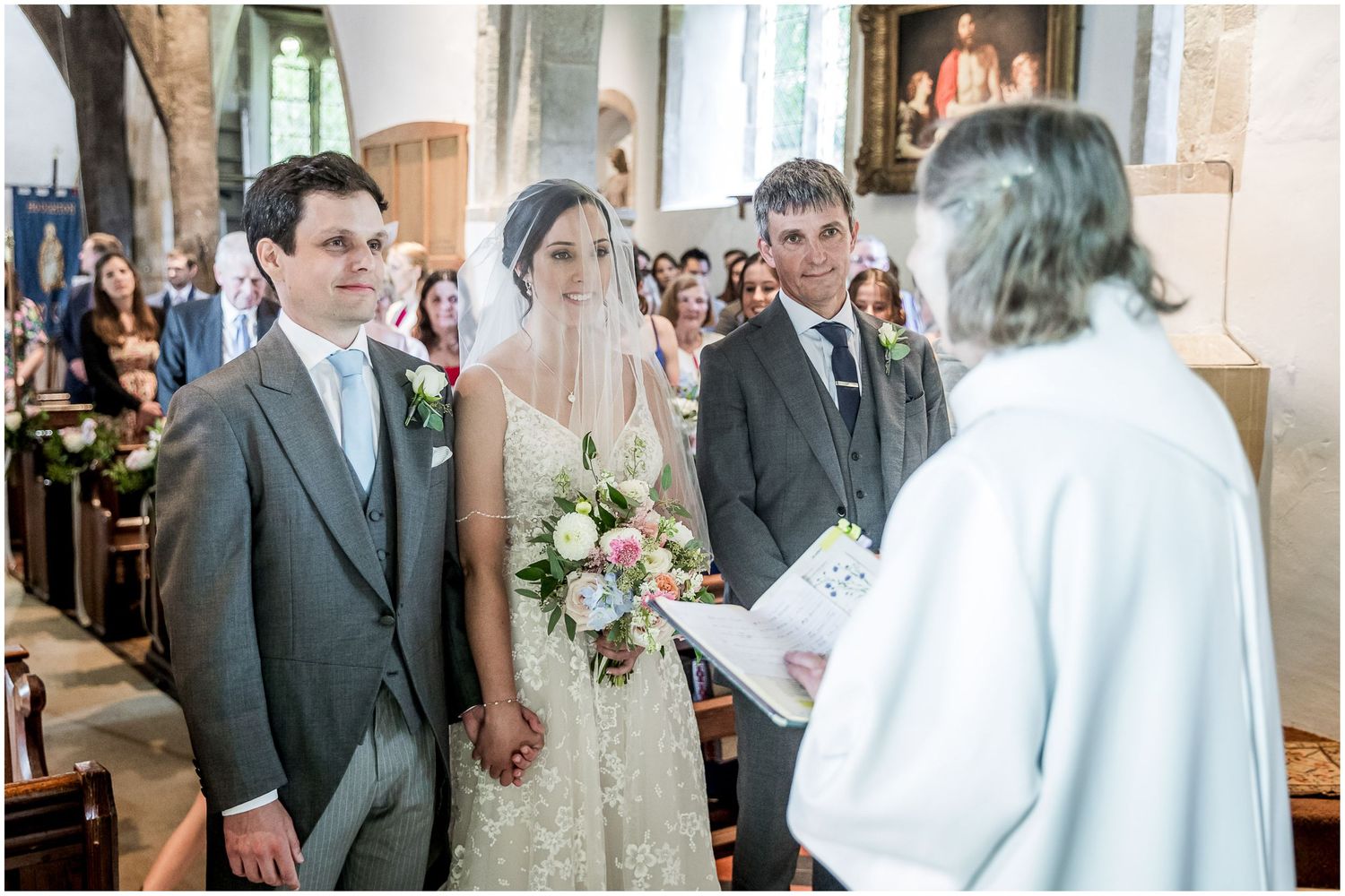 Traditional wedding ceremony taking place in stone church with arched windows.