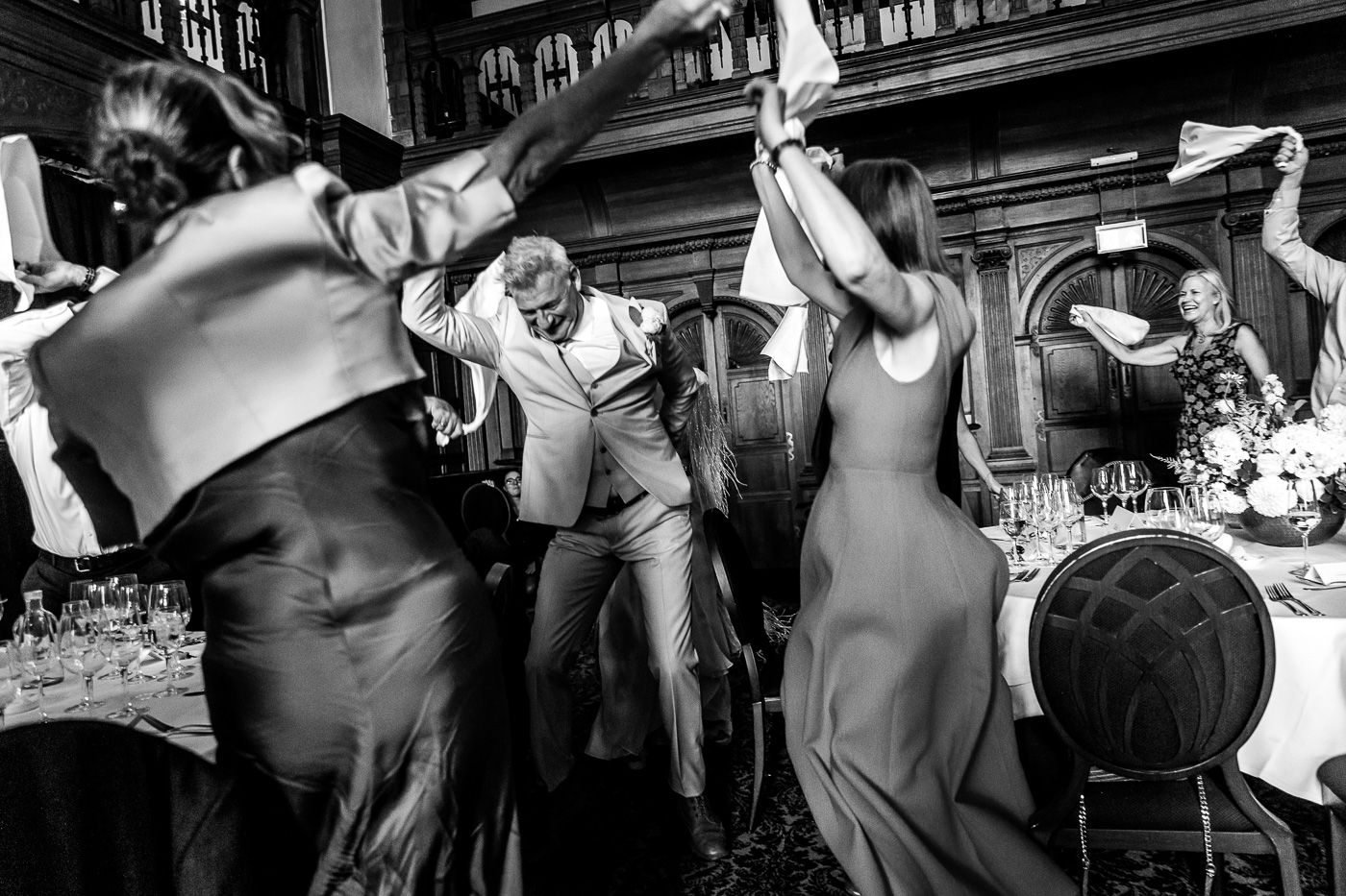 Wedding party dances and celebrates on a dark dance floor at the reception.