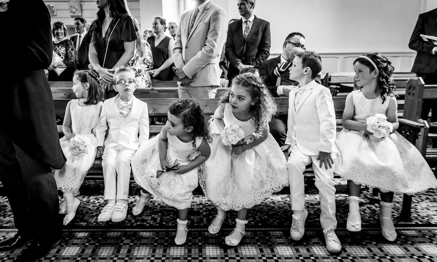 Wedding party members seated in a row on vintage furniture.