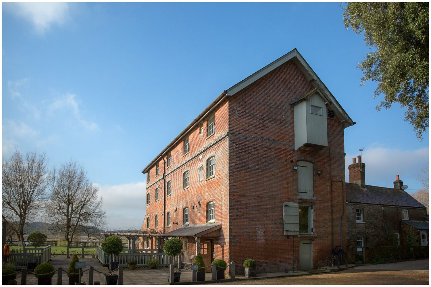 Row of traditional red brick houses with white trim under blue sky.