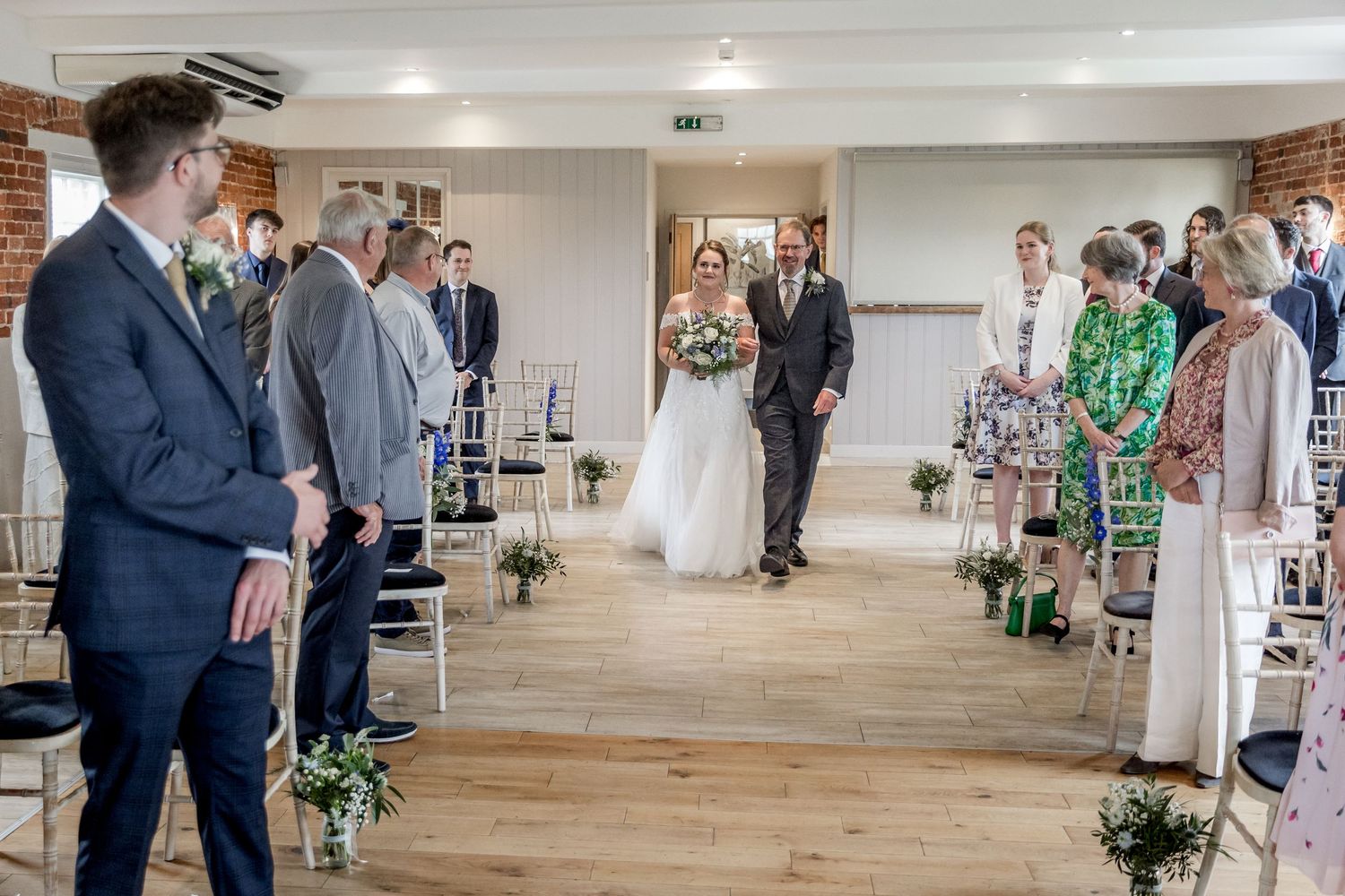 Panoramic view of a modern wedding venue with exposed brick walls and natural lighting.