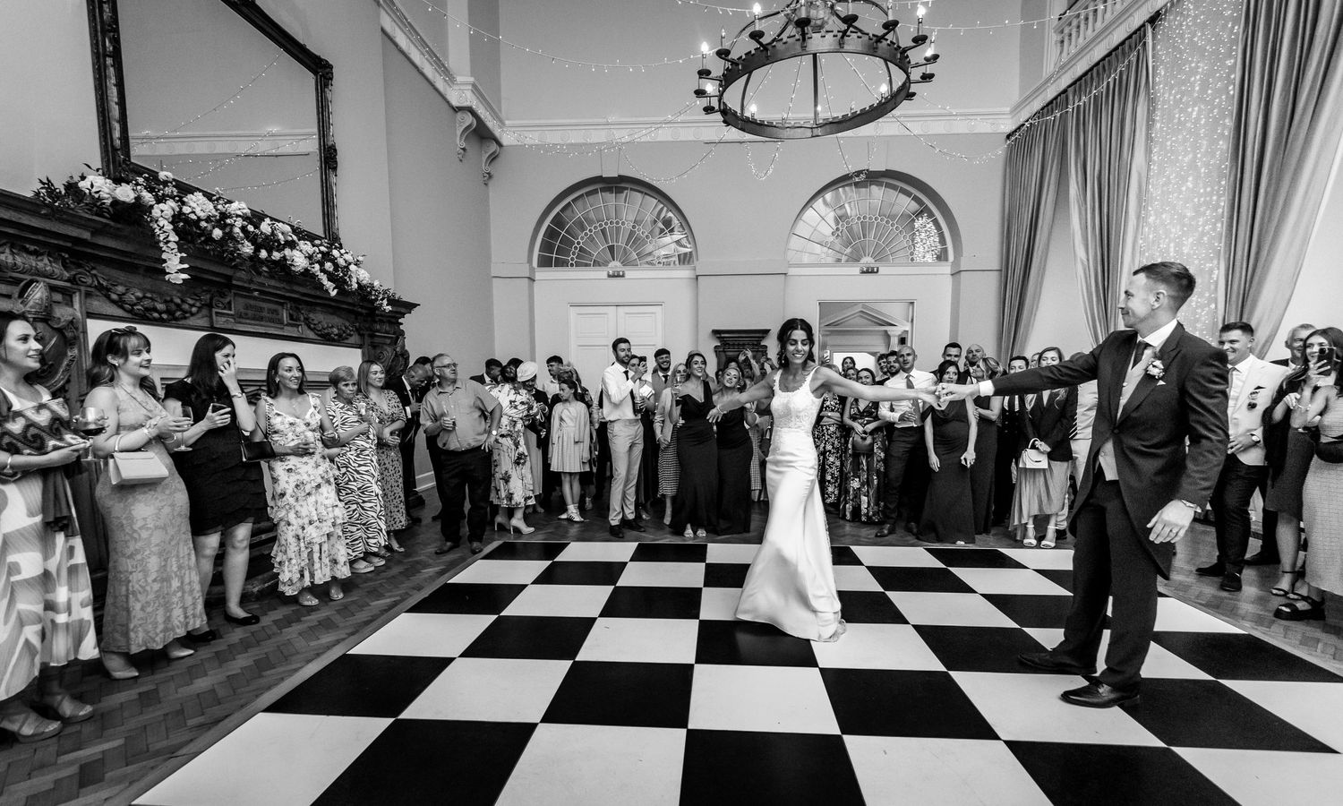 Guests dancing in formation during a wedding reception on a black and white checkered floor.